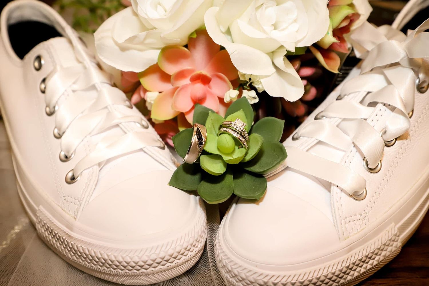 White wedding Converse sneakers with wedding rings and a succulent rest beside a floral bouquet in Jacksonville Florida.