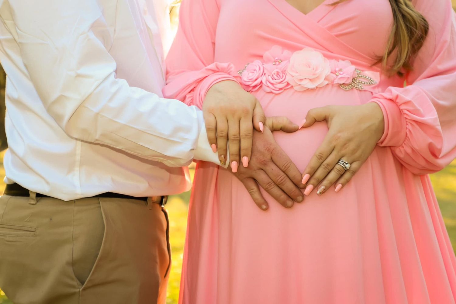 Maternity portrait of a couple forming a heart shape with their hands on a pregnant belly outdoors in Gainesville, Florida.