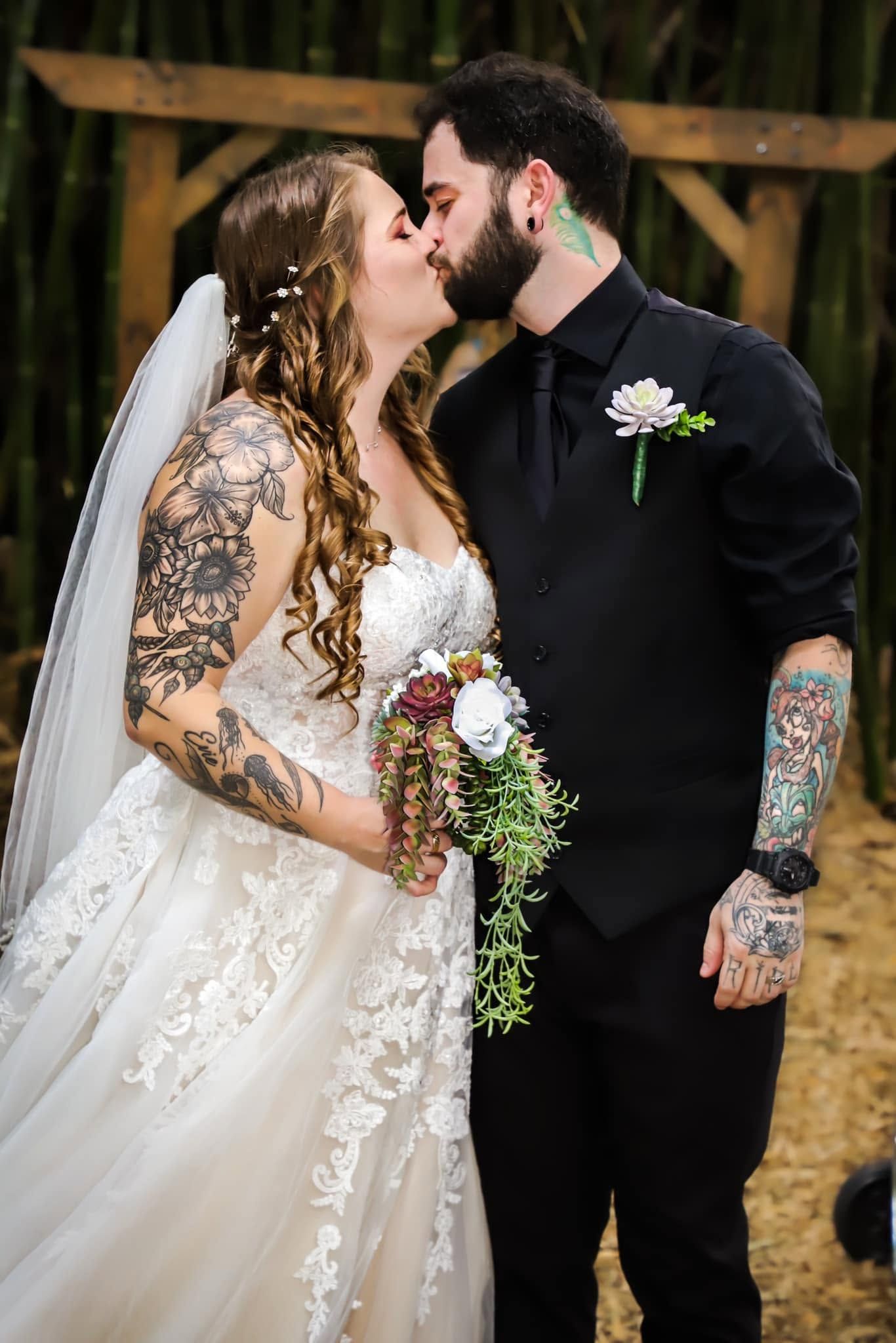 Tattooed bride and groom kiss at the altar, with the bride holding a boho bouquet in Gainesville, Florida.