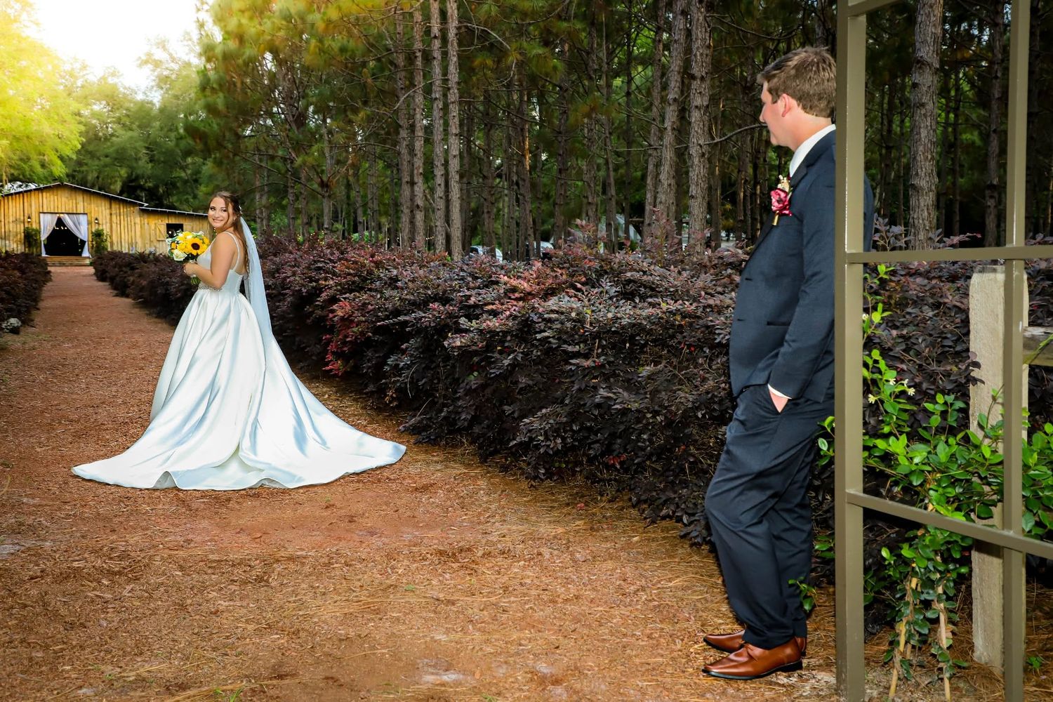 Bride and groom stand outside an elegant building, with the bride’s long cathedral veil trailing behind them.