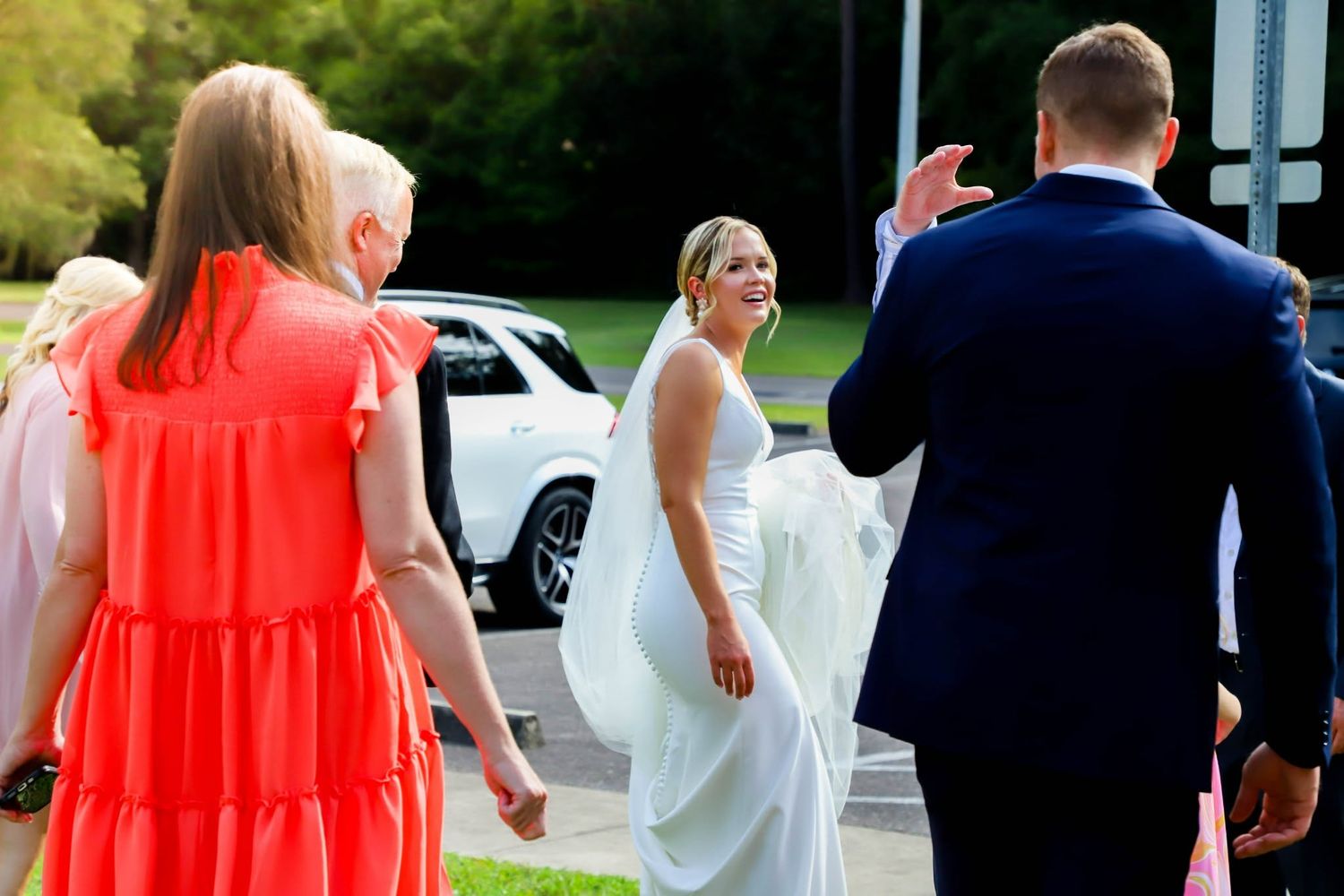 Bride in white gown walking toward guests at an outdoor wedding venue.