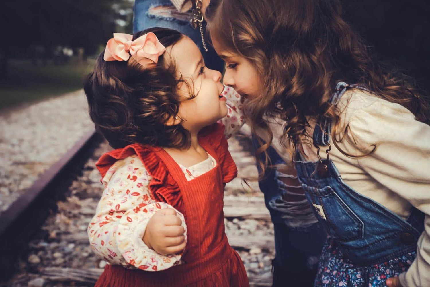 Fall mini session featuring two young girls sharing a sweet kiss on railroad tracks in Lake City, Florida.