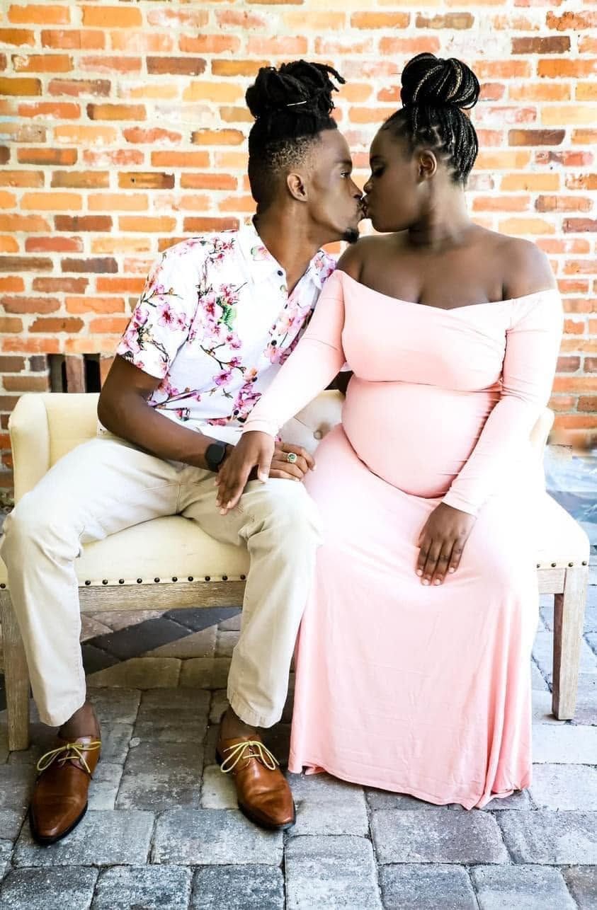 A couple shares a kiss as the pregnant woman in a pink gown cradles her baby bump in Winter Park Florida