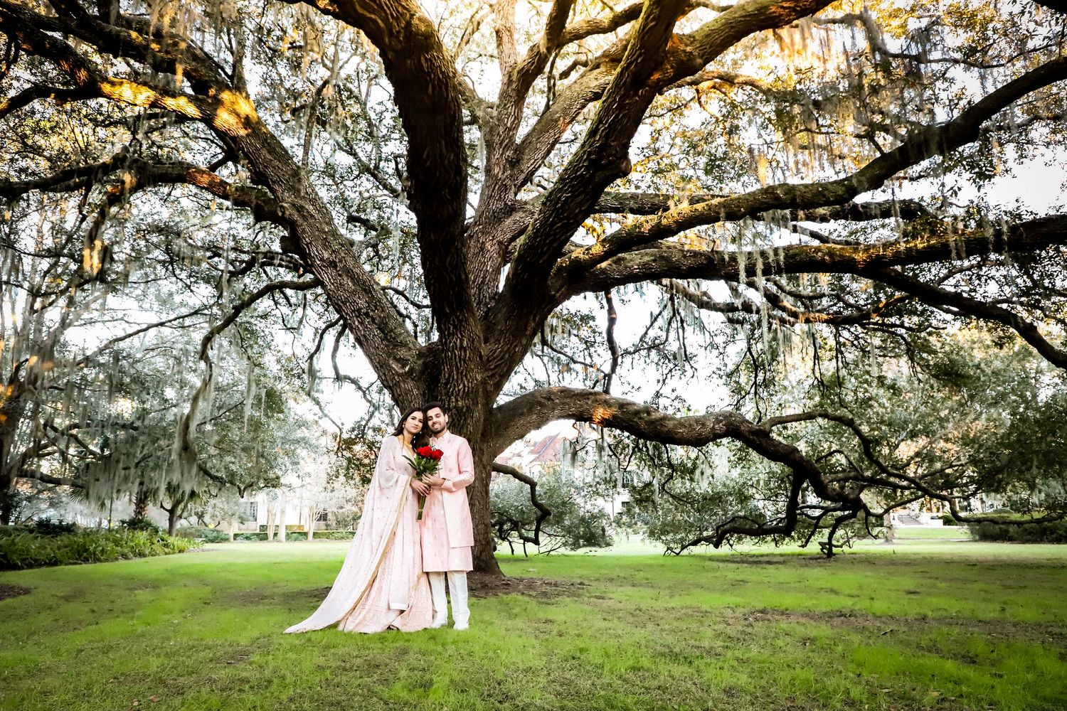 Couple embracing beneath a large moss-covered oak tree during an outdoor wedding ceremony in Lake City, Florida.