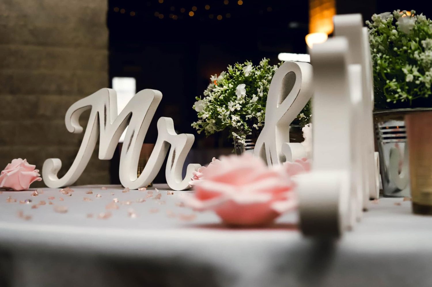 Decorative white Mr and Mrs wedding signs on a reception table with flowers and candles.