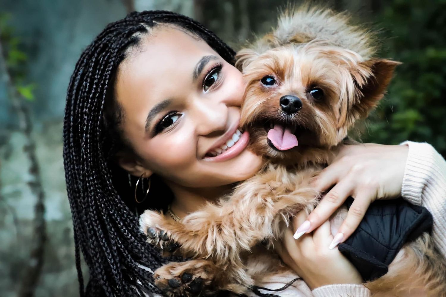 Pet-friendly portrait of a young woman with braids hugging a Yorkshire Terrier outdoors in Lake City, Florida.