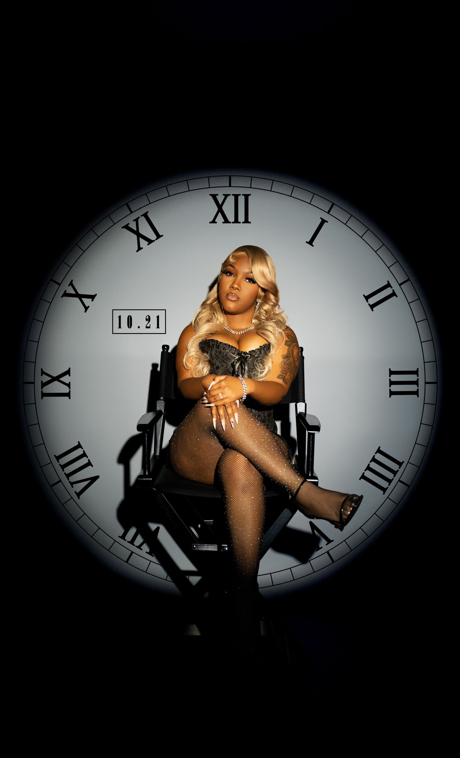 Woman in sparkly outfit sits in director chair before large clock face in dramatic lighting.