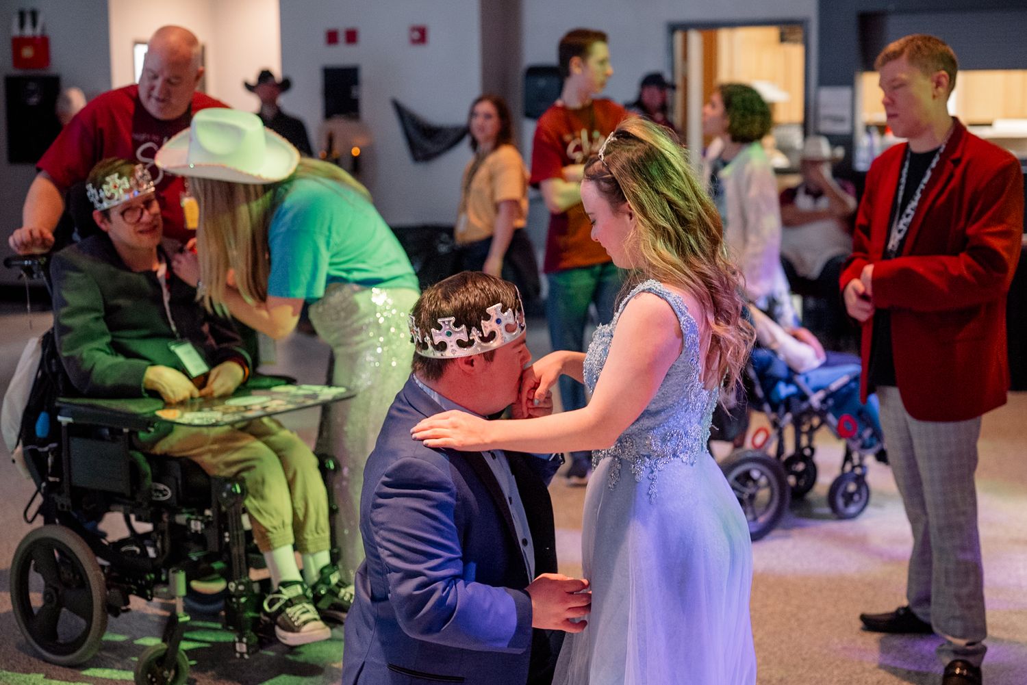 Crowned guest kisses partner’s hand at Night to Shine, a sweet, romantic moment celebrating love, dignity, and inclusive joy on the dance fl