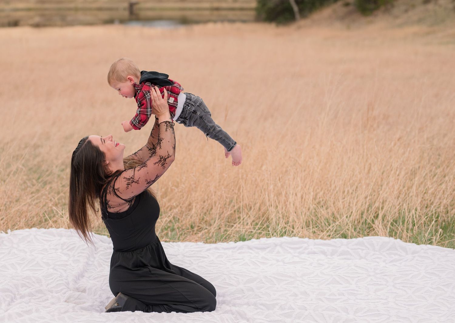 Mother lifting baby boy in field, candid Colorado family photography, natural light Denver photographer