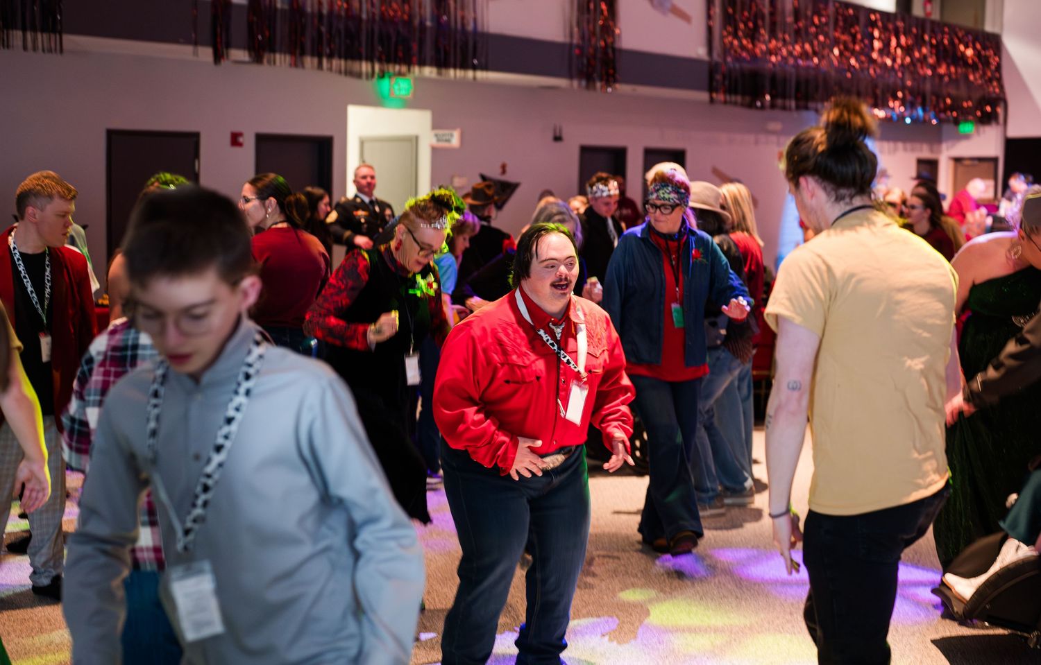 A lively crowd dances under warm event lighting at a Night to Shine celebration in Colorado, featuring a western-themed rodeo atmosphere