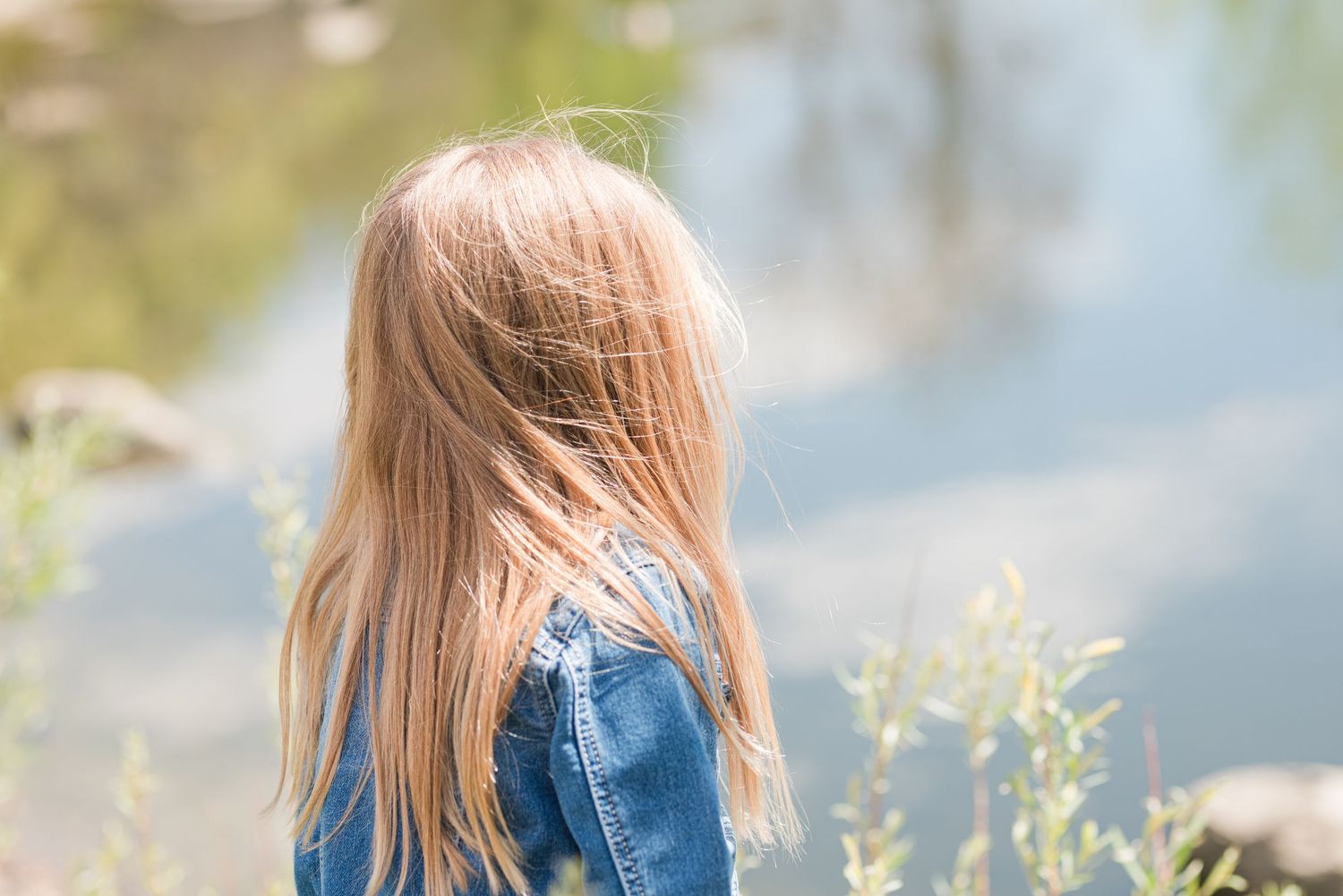 Back view of young girl looking at water, outdoor Colorado family photography, natural light Denver photographer