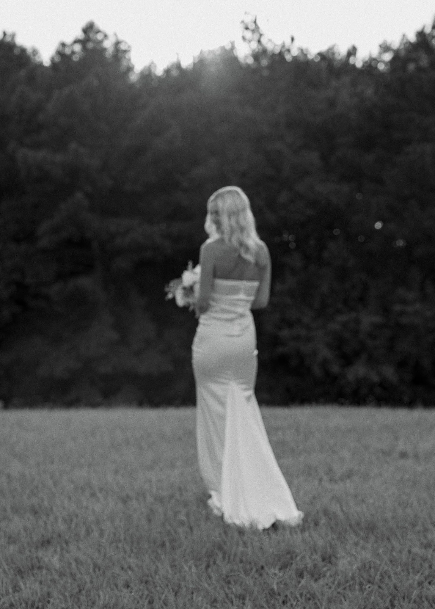 Romantic black and white photo of a couple dancing in a meadow.