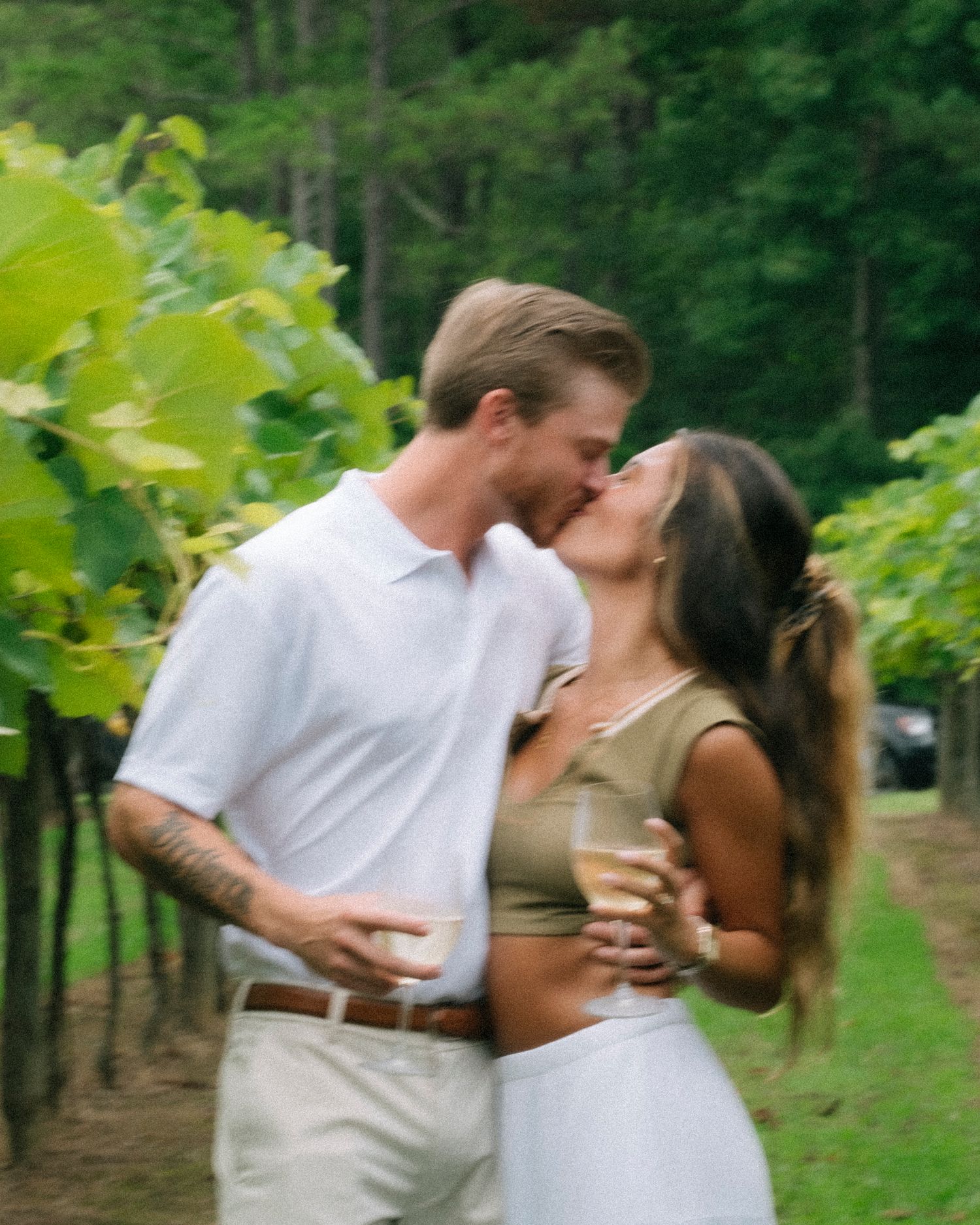 Couple embraces romantically in a lush vineyard setting during a photo session.