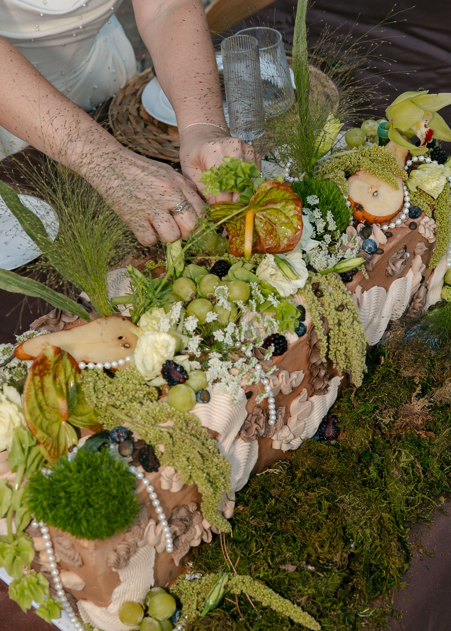 Rustic floral arrangement being assembled with moss, greenery and natural elements.