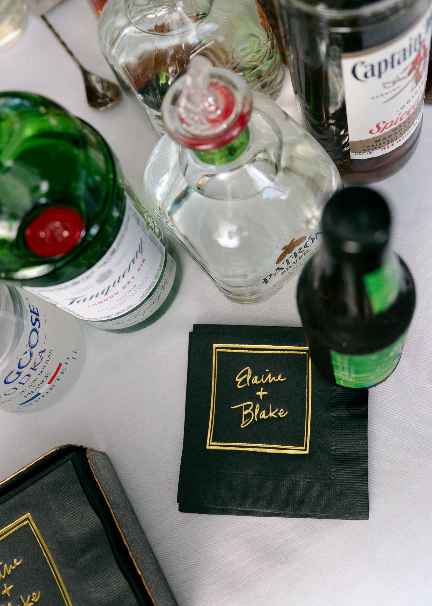 Assorted liquor bottles and cocktail glasses arranged on a dark surface with elegant coasters.