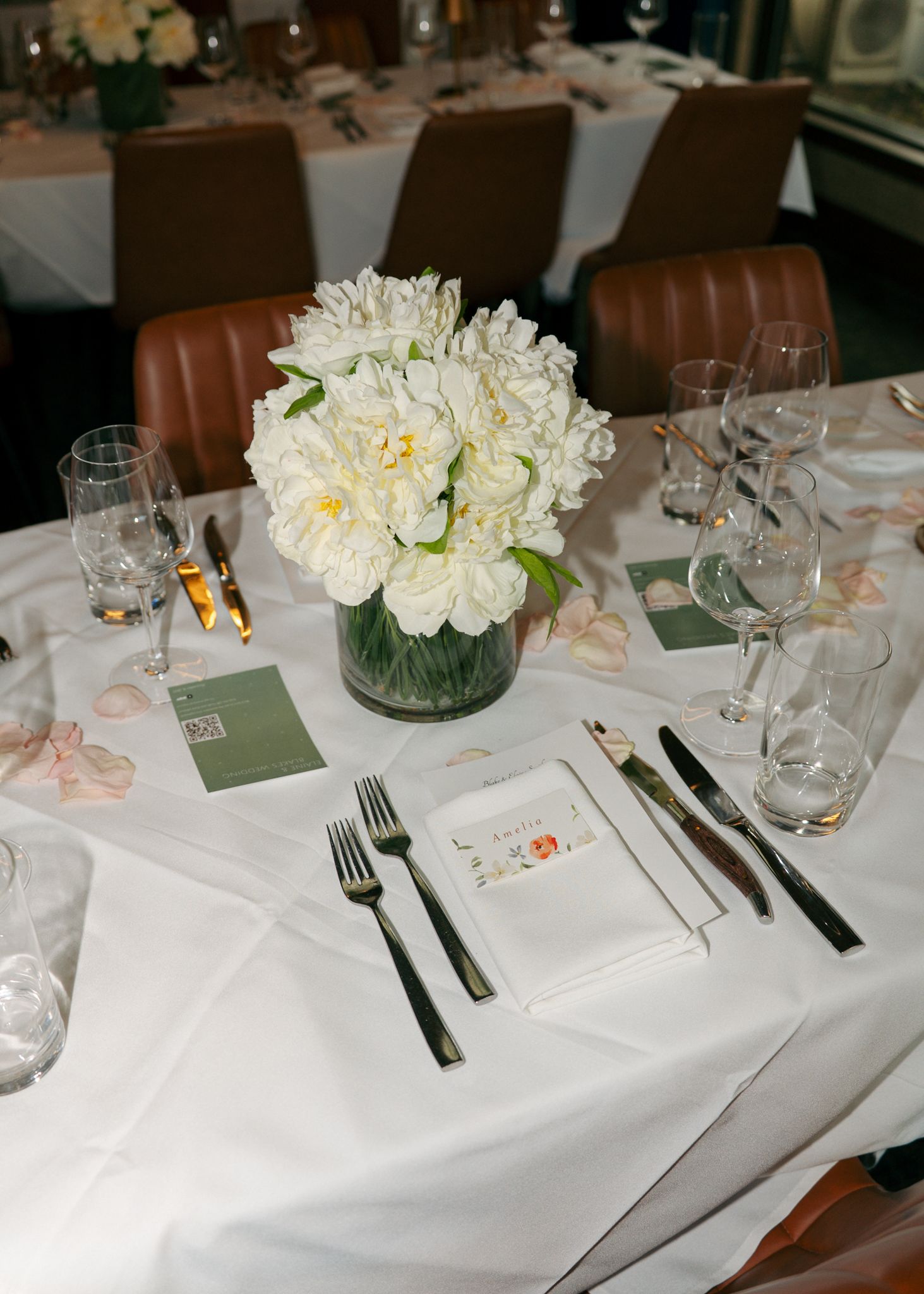 Formal table settings with white linens, glassware and floral centerpieces.