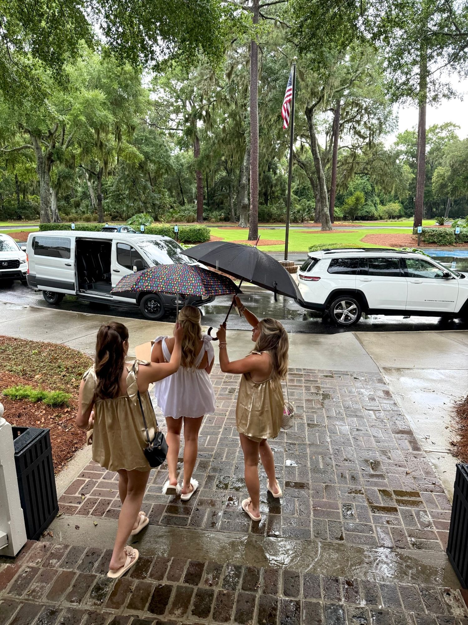 People with umbrellas walking on wet brick pavement during a rainy day.