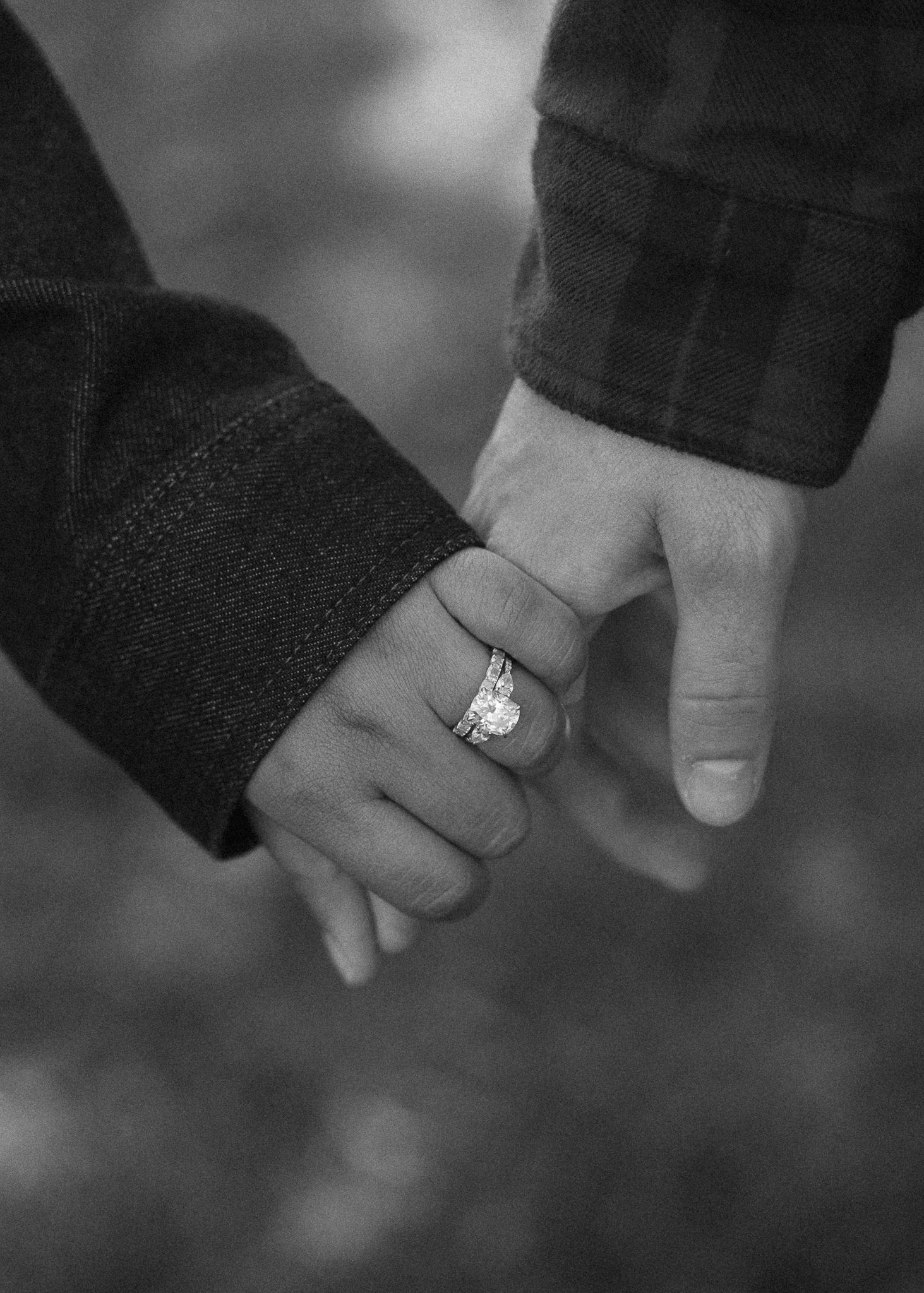 Black and white photo of hands with engagement and wedding rings.