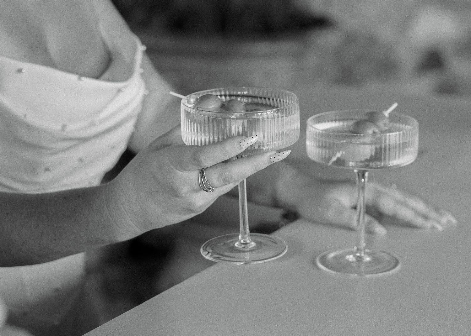Two champagne coupes clinking together in black and white photography.