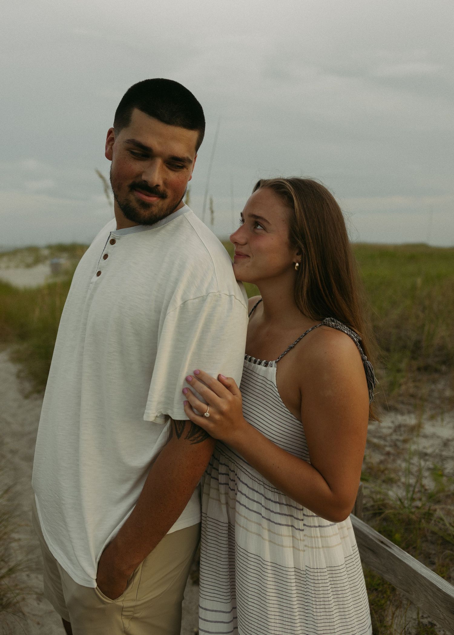 Couple sharing a tender moment on a cloudy beach.