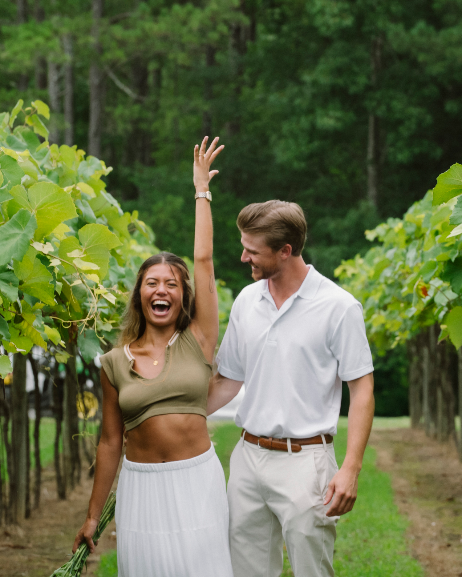 Candid moment of laughter between couple in a vineyard setting.