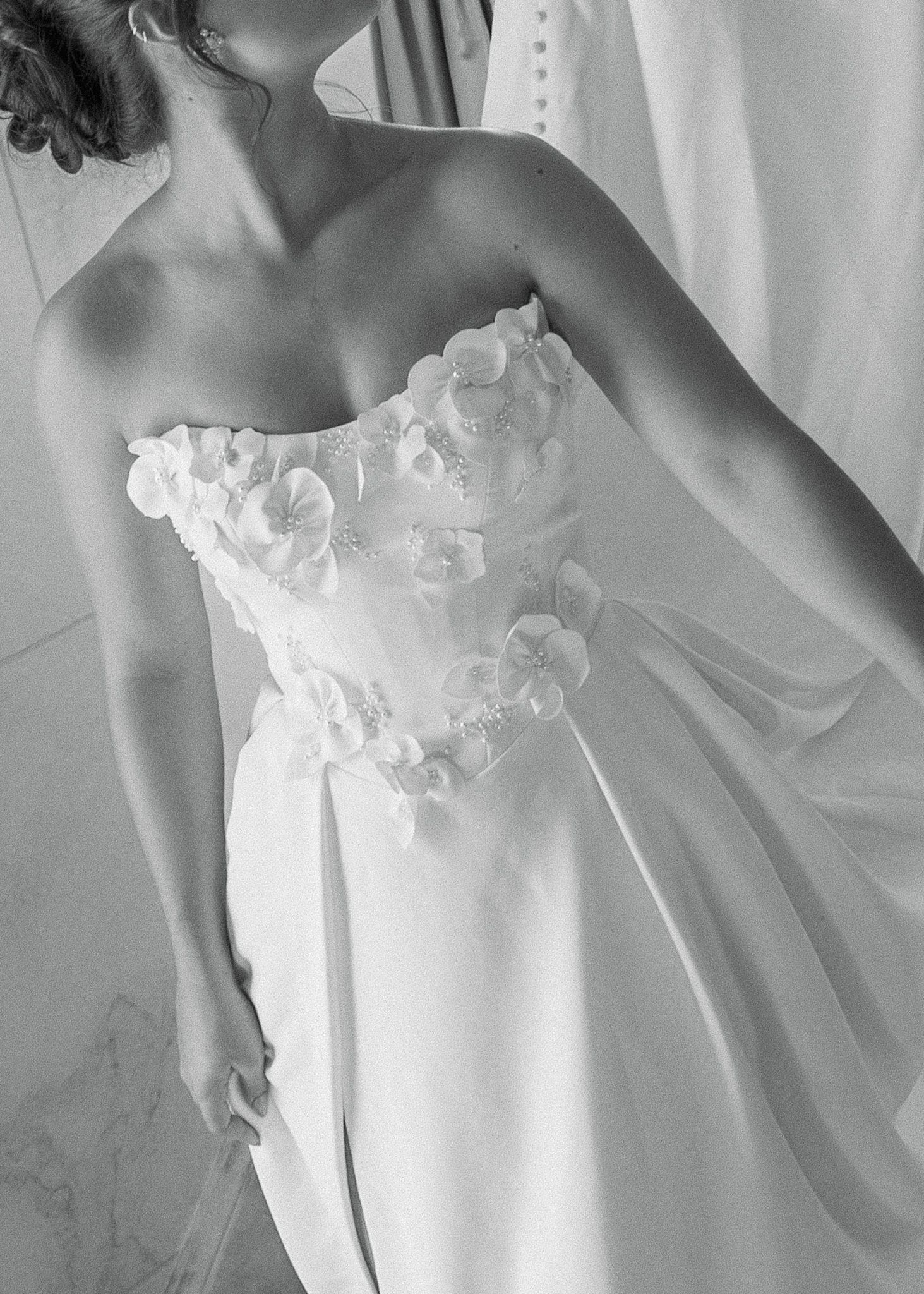 Elegant white wedding dress with floral appliques and strapless sweetheart neckline shown in black and white photography.