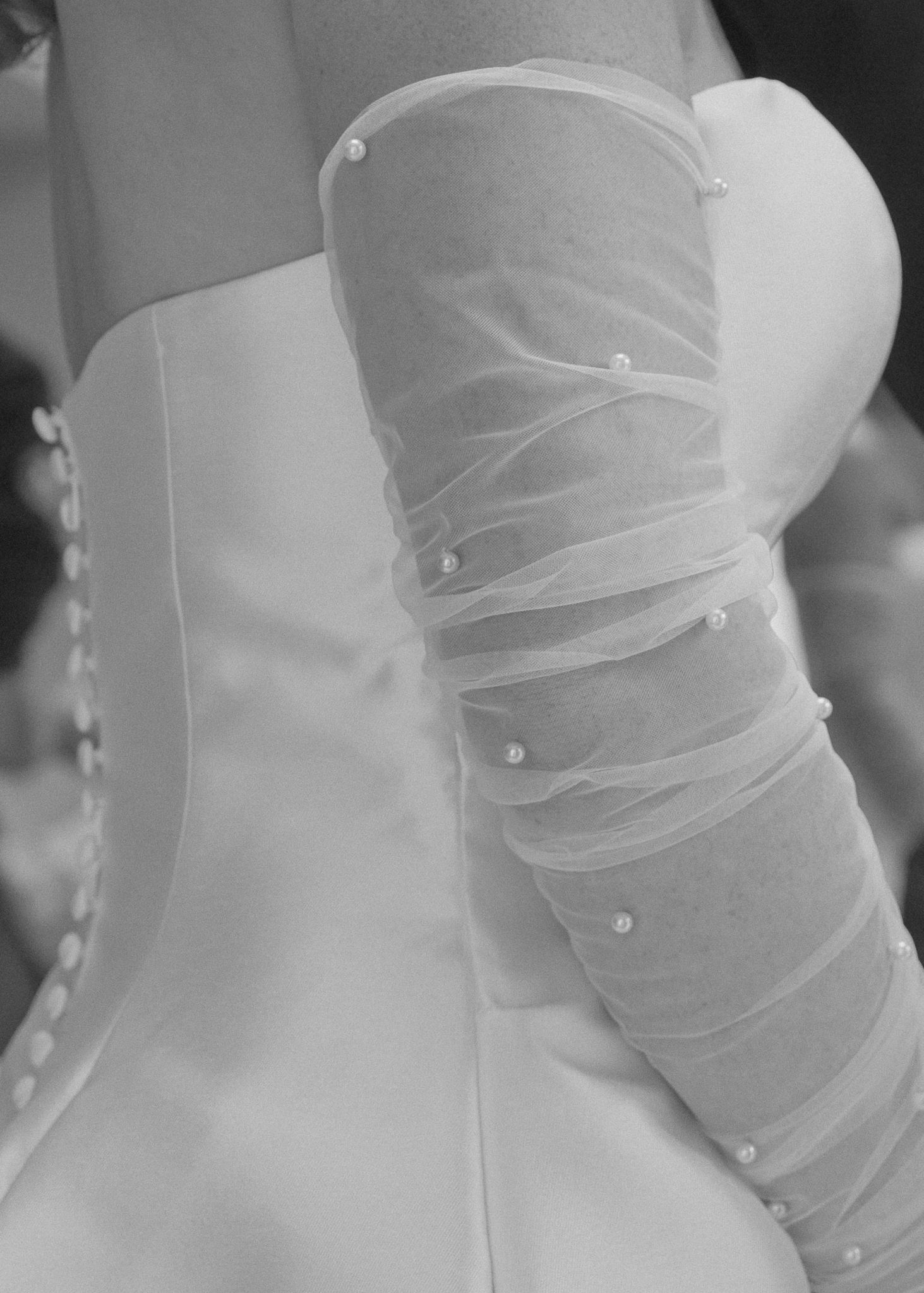 Close-up detail of a white wedding dress bodice with delicate button closures.