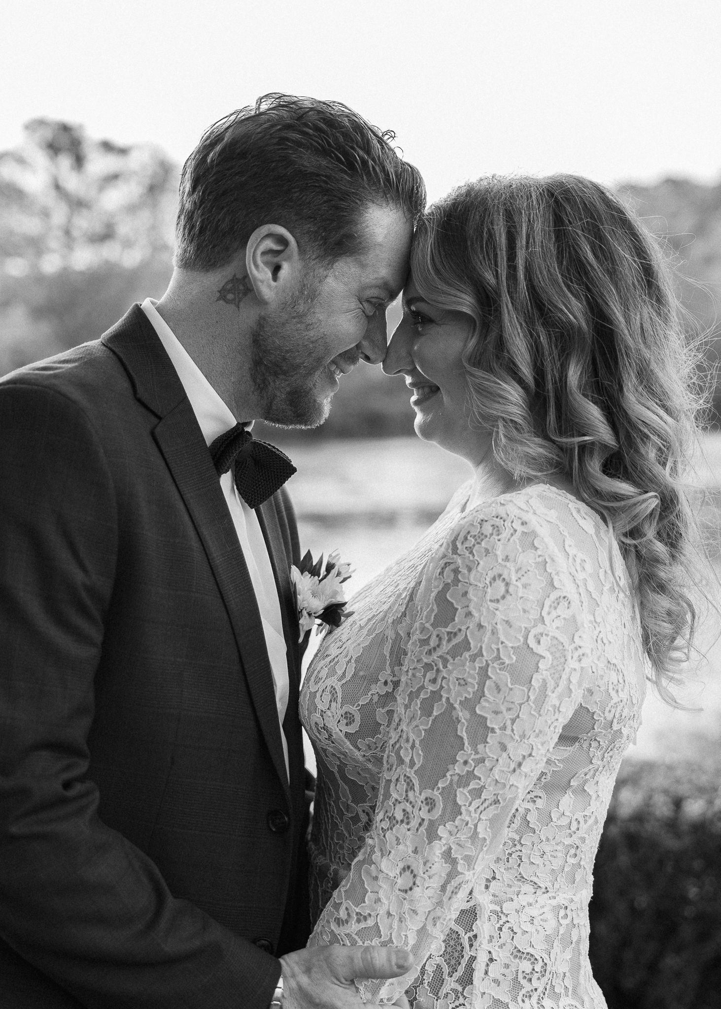 A romantic black and white portrait of a wedding couple in formal attire.