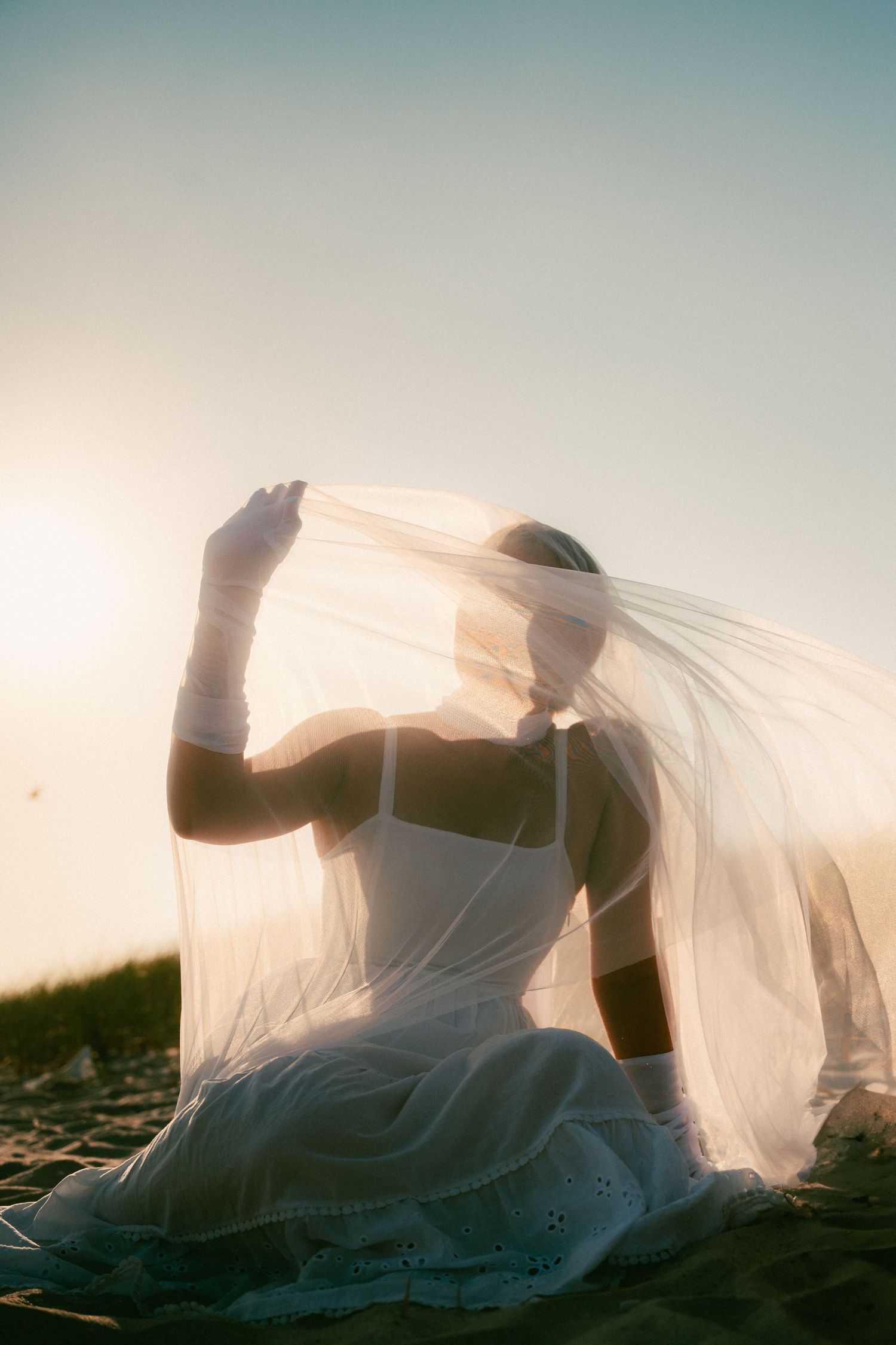 Artistic silhouette series of a bride in flowing veil against a sunset sky.