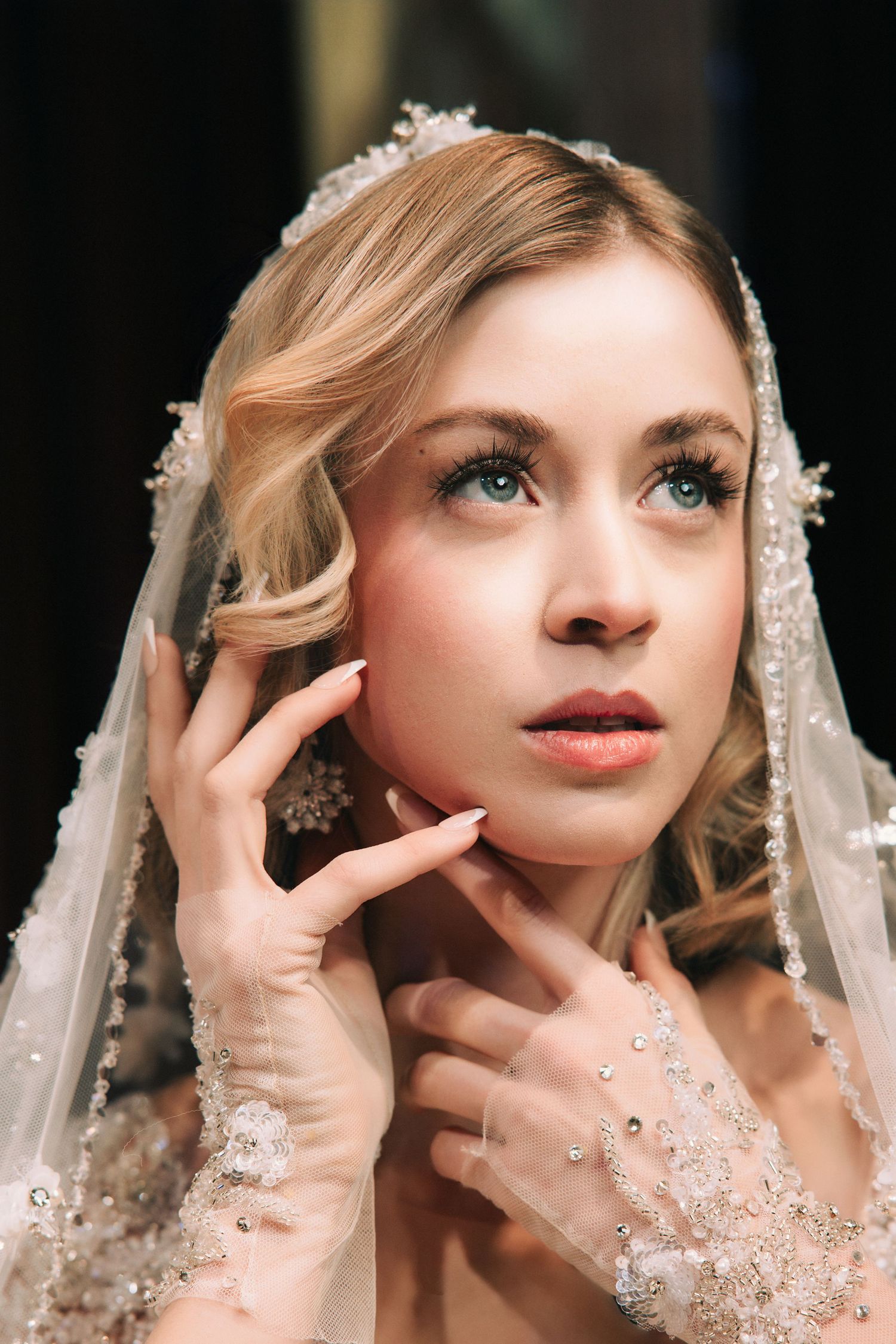 A bride wearing a delicate lace veil poses in an artistic sequence of ethereal portraits with dramatic lighting.