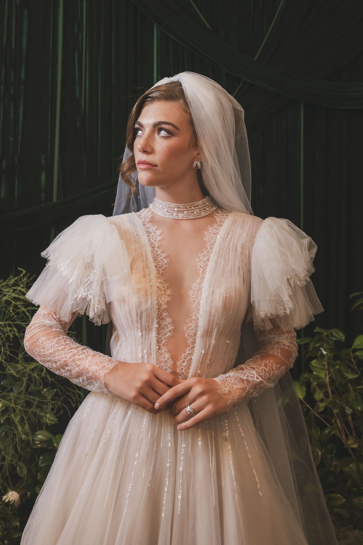 Ethereal bridal portrait featuring a romantic sheer lace gown with dramatic puffy sleeves in a garden setting.