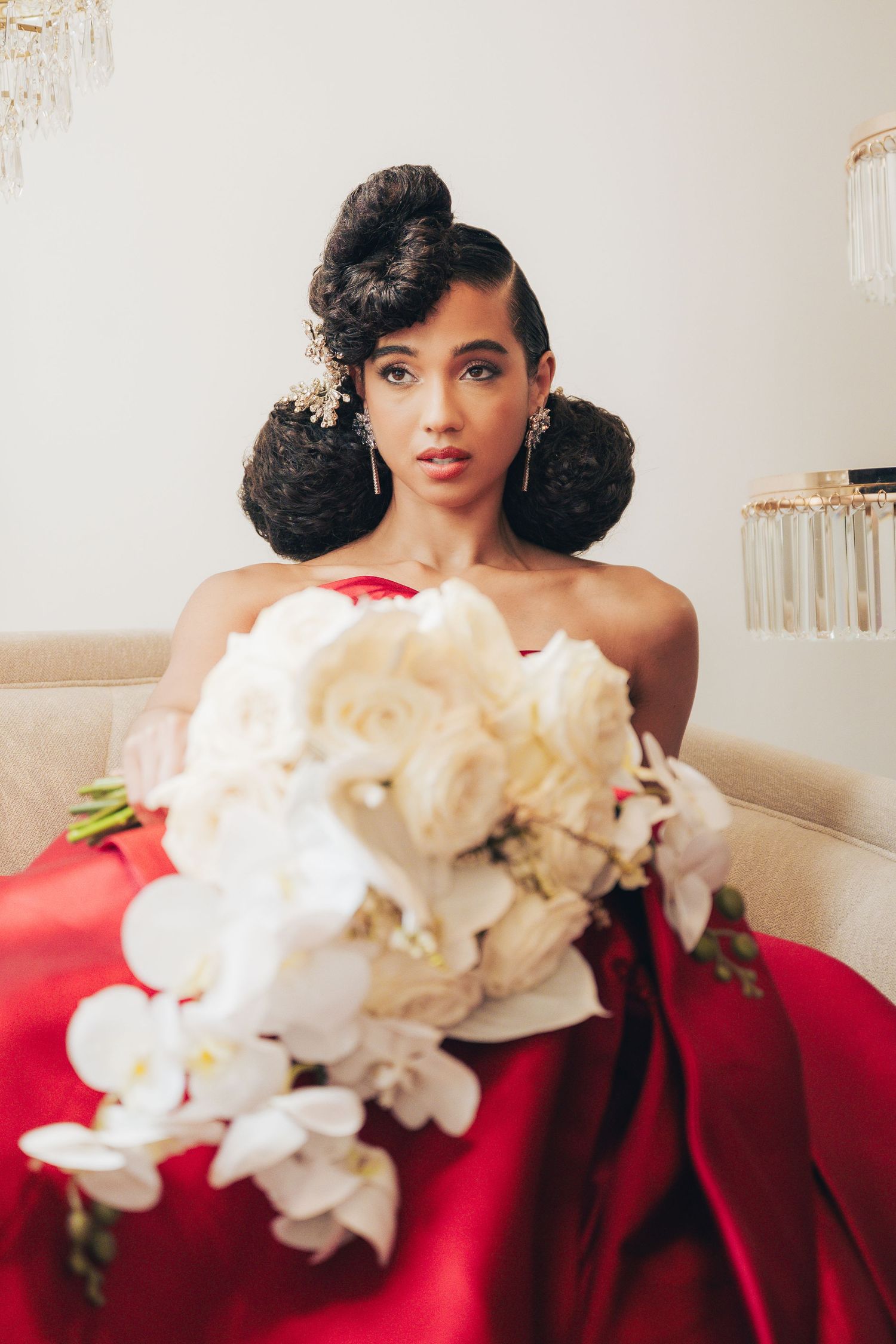 Close-up fashion portraits with red gown and white orchid bouquet against light background.