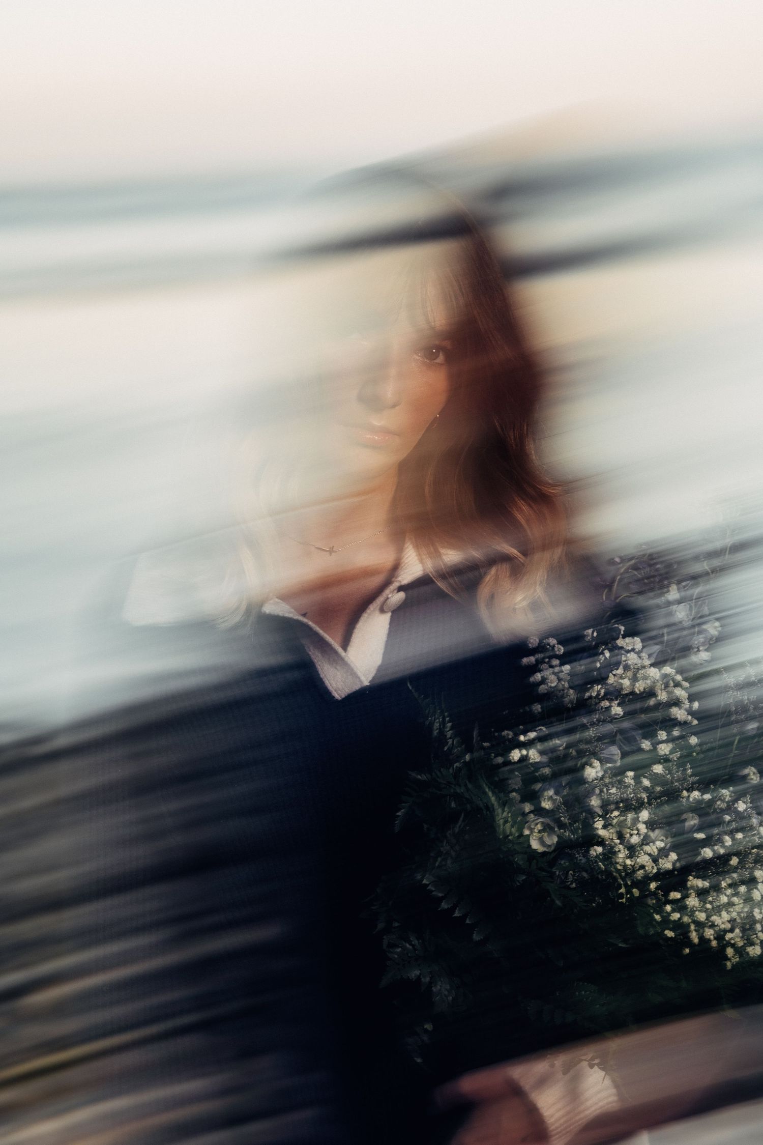 Abstract motion-blur photograph with soft blue tones and white flowers in nature.