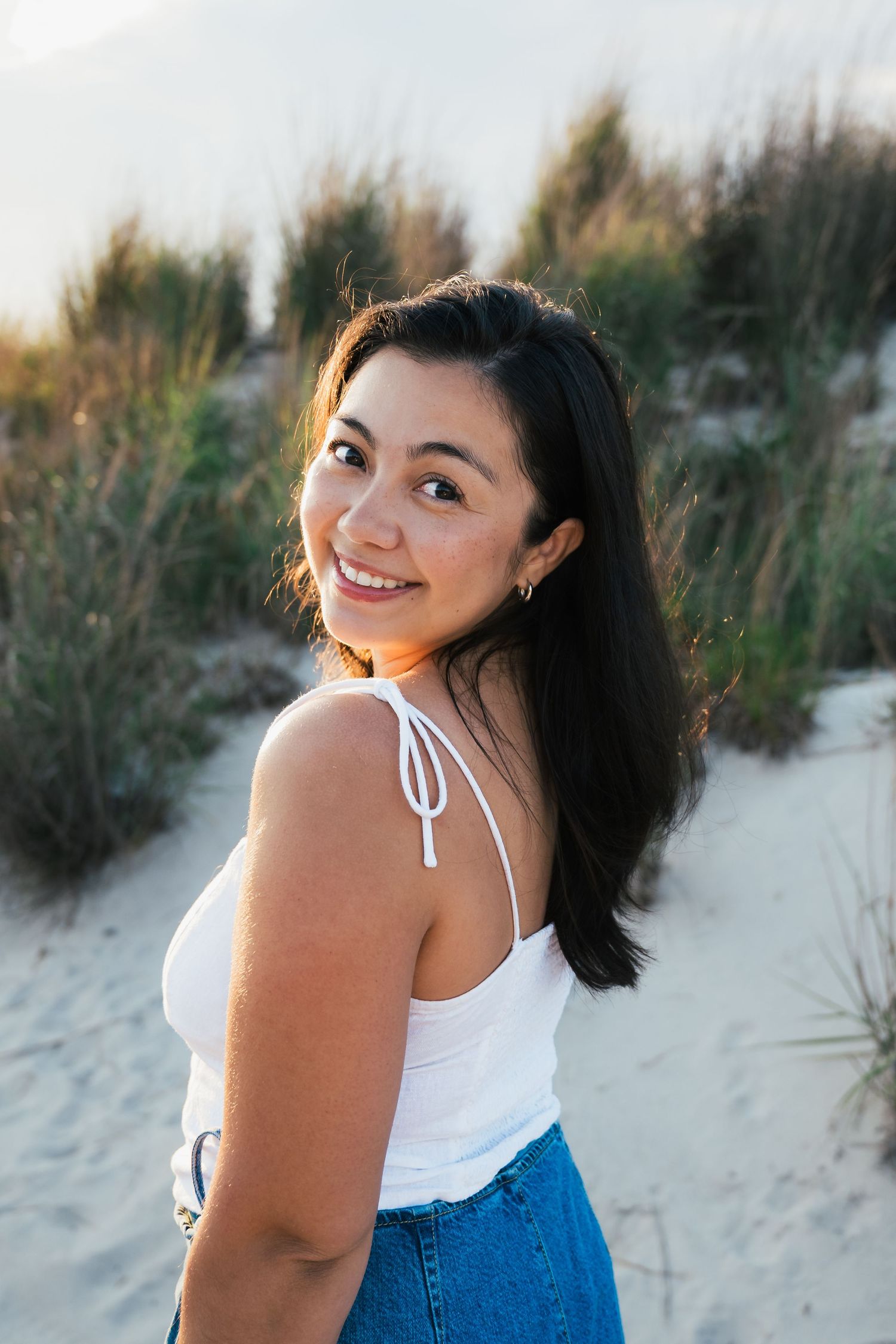 Summer beach portrait session with casual attire and natural dunes in the background.