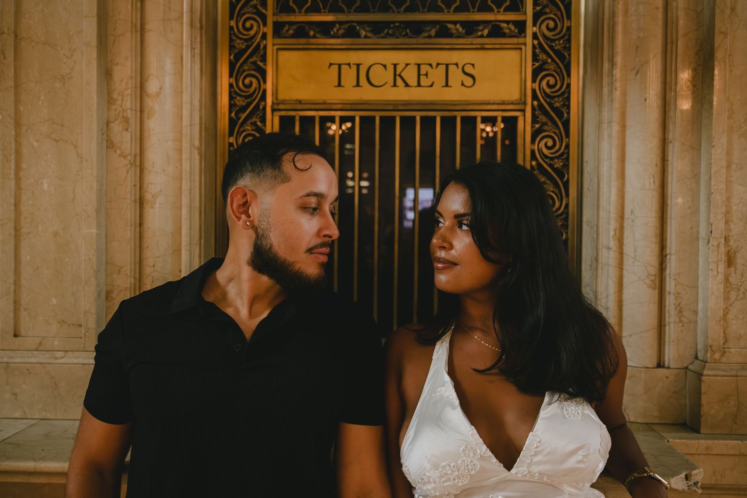 Couple sharing an intimate moment in an ornate vintage theater hallway.