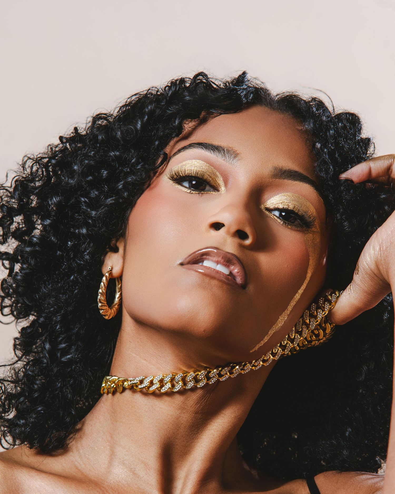 Fashion beauty portrait with curly hair and gold jewelry in artistic poses against neutral background.