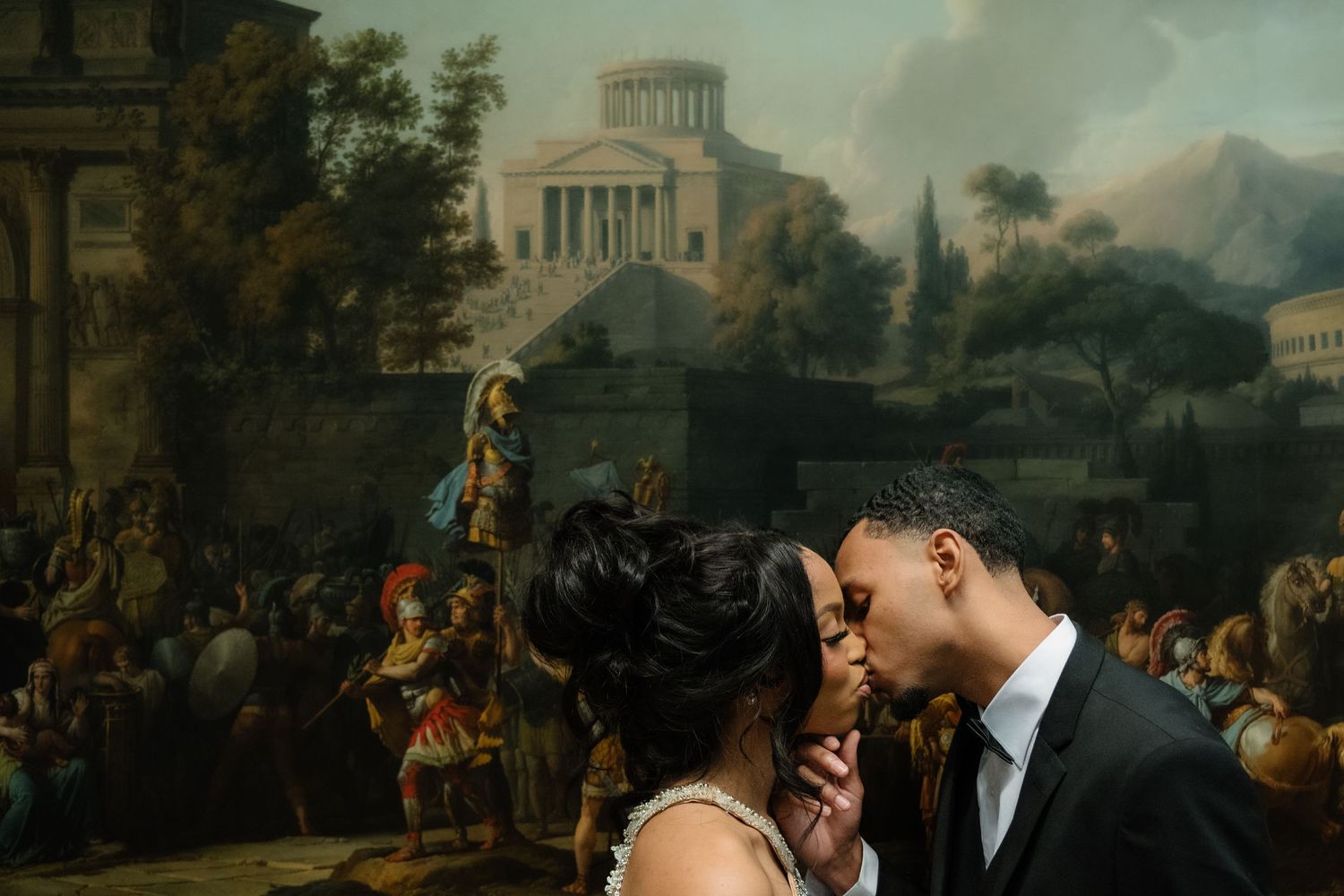 A classical painting depicting figures in an ornate garden setting with architectural elements and distant mountains.