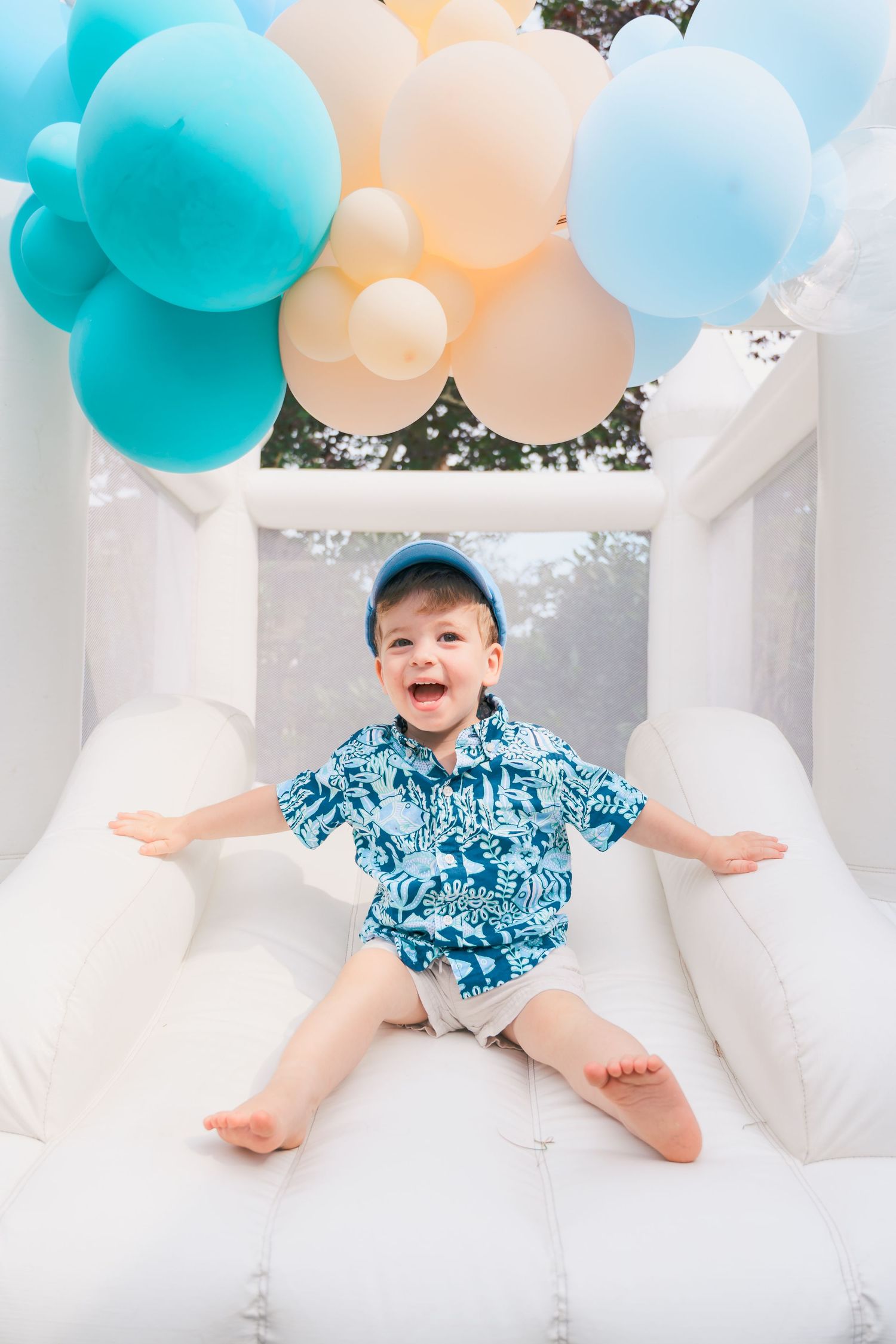 Baby photoshoot setup with turquoise and peach balloons on white furniture.