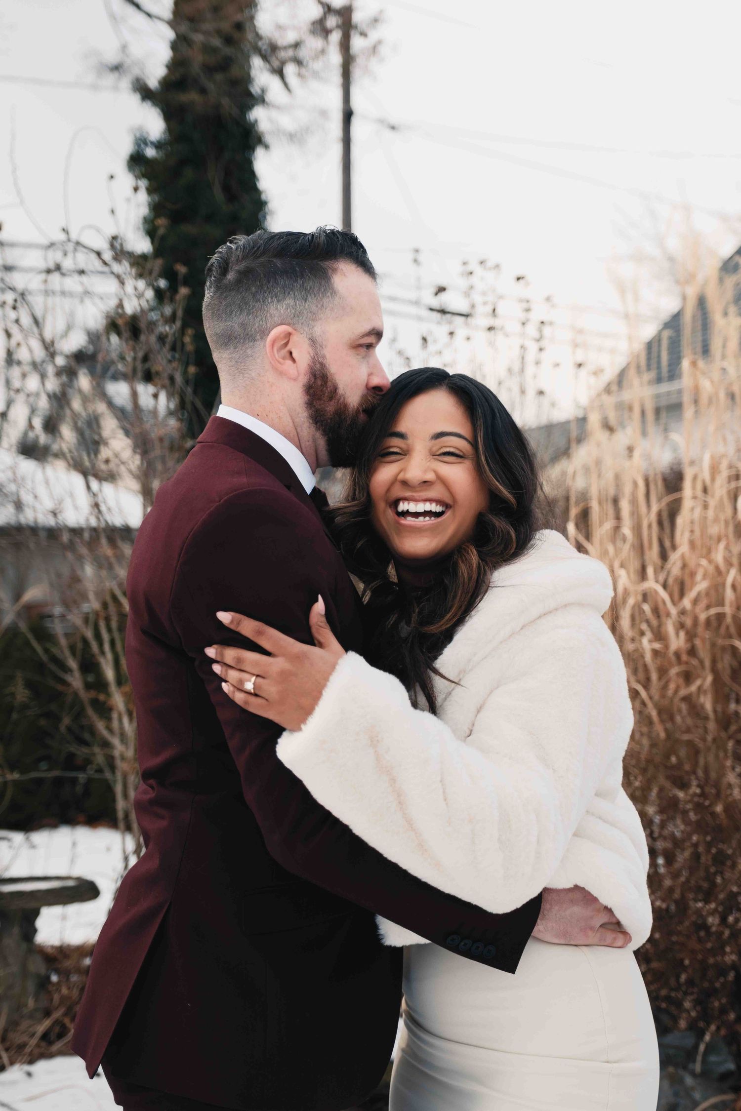 Winter engagement photos showing couple embracing and laughing in warm coats.