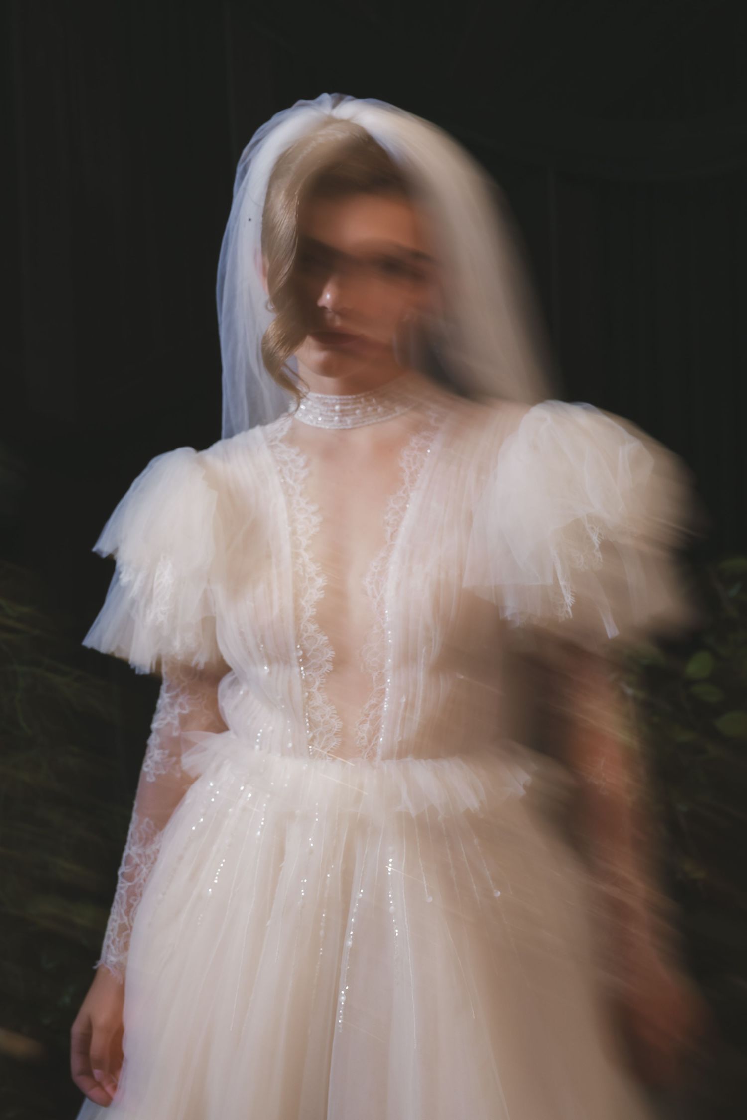 Dreamy motion-blur portrait of a bride in a classic white wedding dress with delicate lace details.
