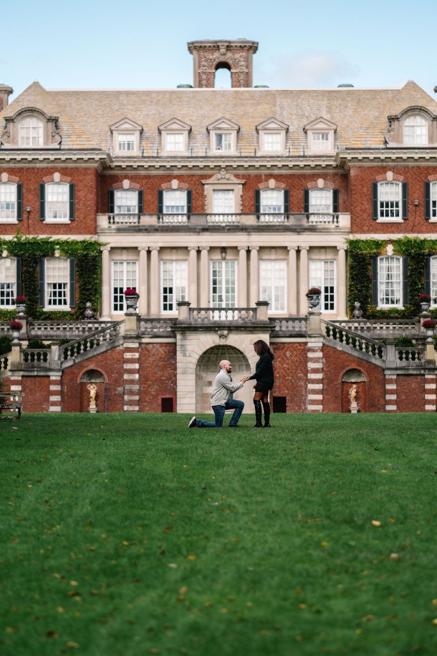 Stately brick mansion with white trim and dormer windows on a manicured green lawn.