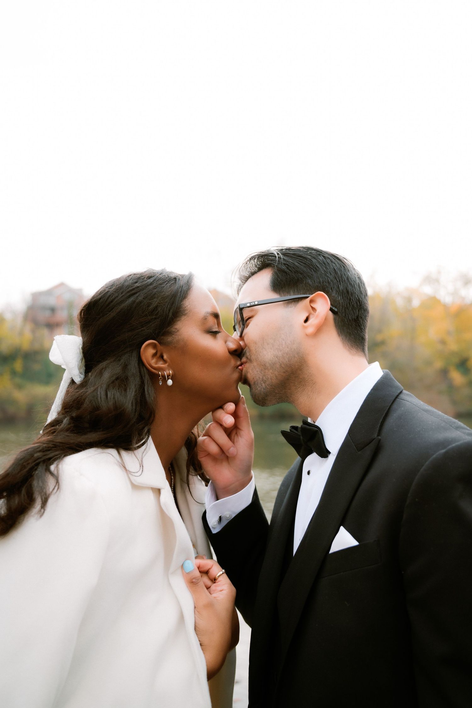 A couple shares a romantic kiss during their wedding ceremony on an autumn day.