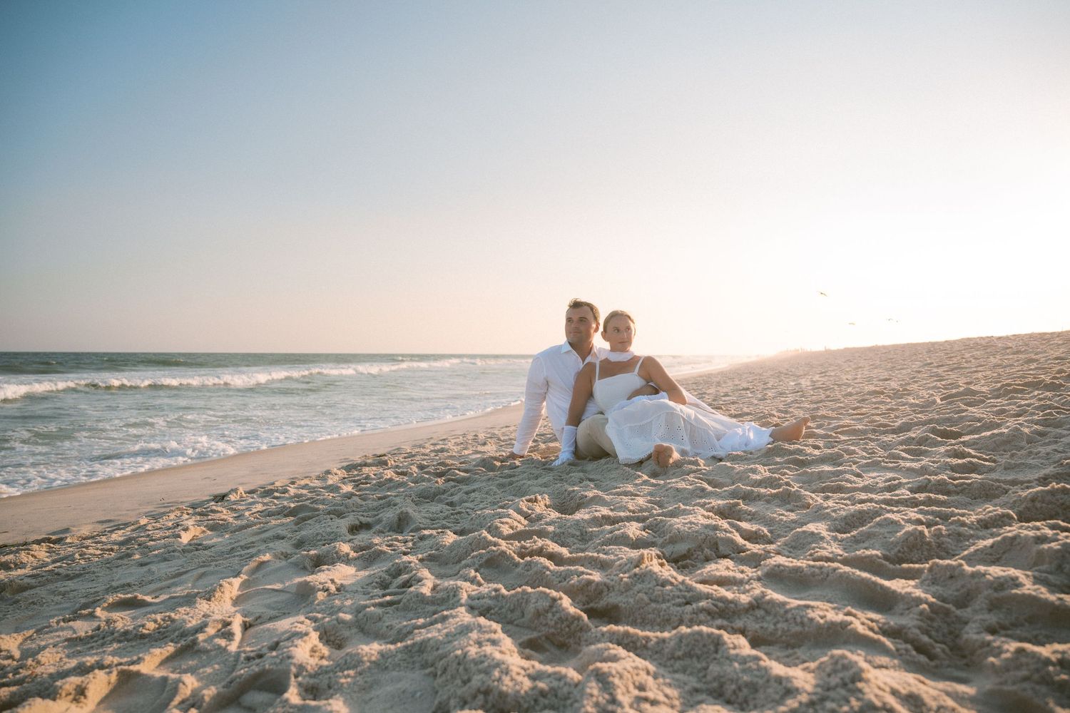 Romantic beach photoshoot at sunset with soft golden lighting.