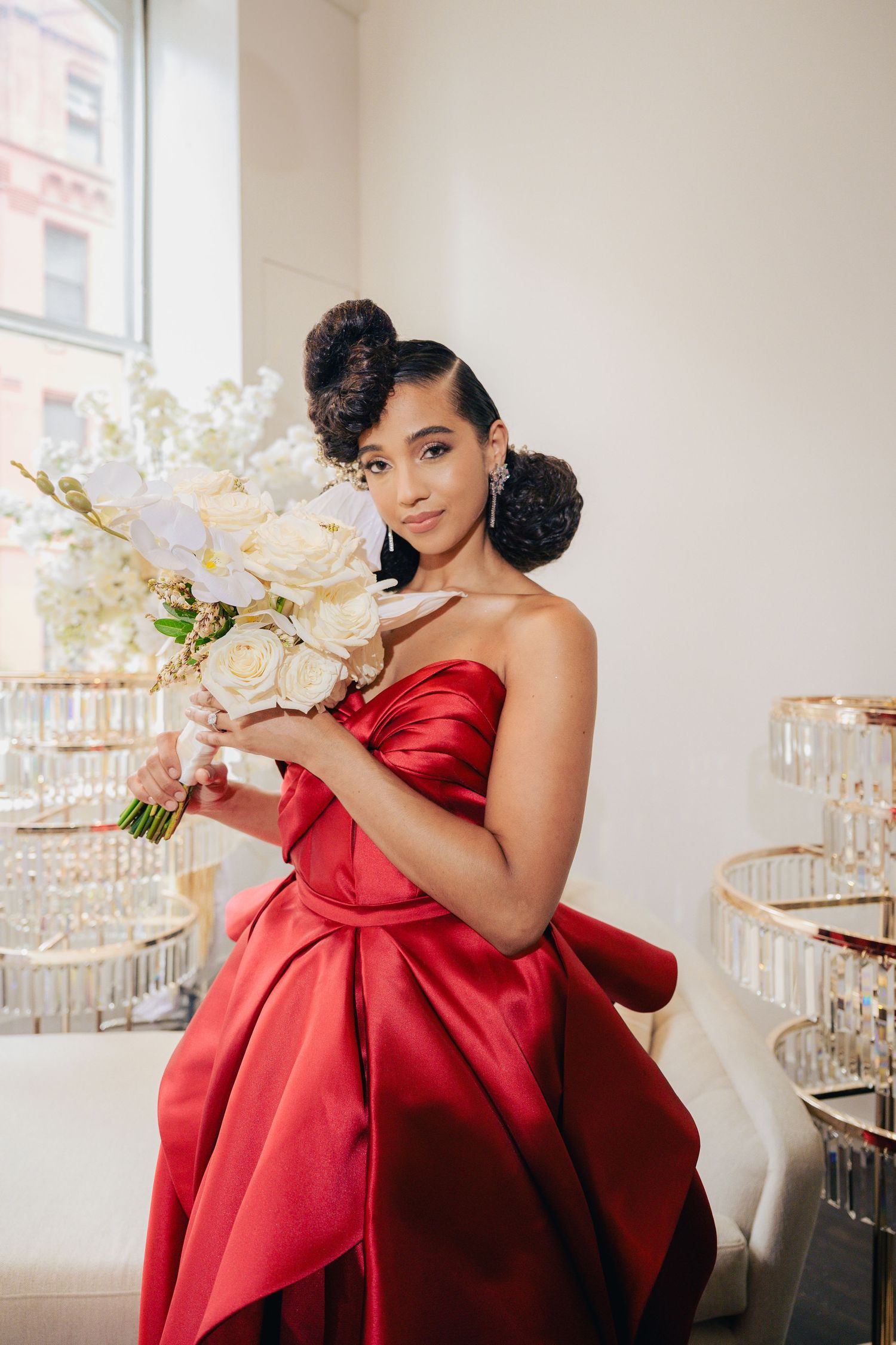 Elegant photo series featuring a red satin ball gown and white orchid bouquet in a bright interior.