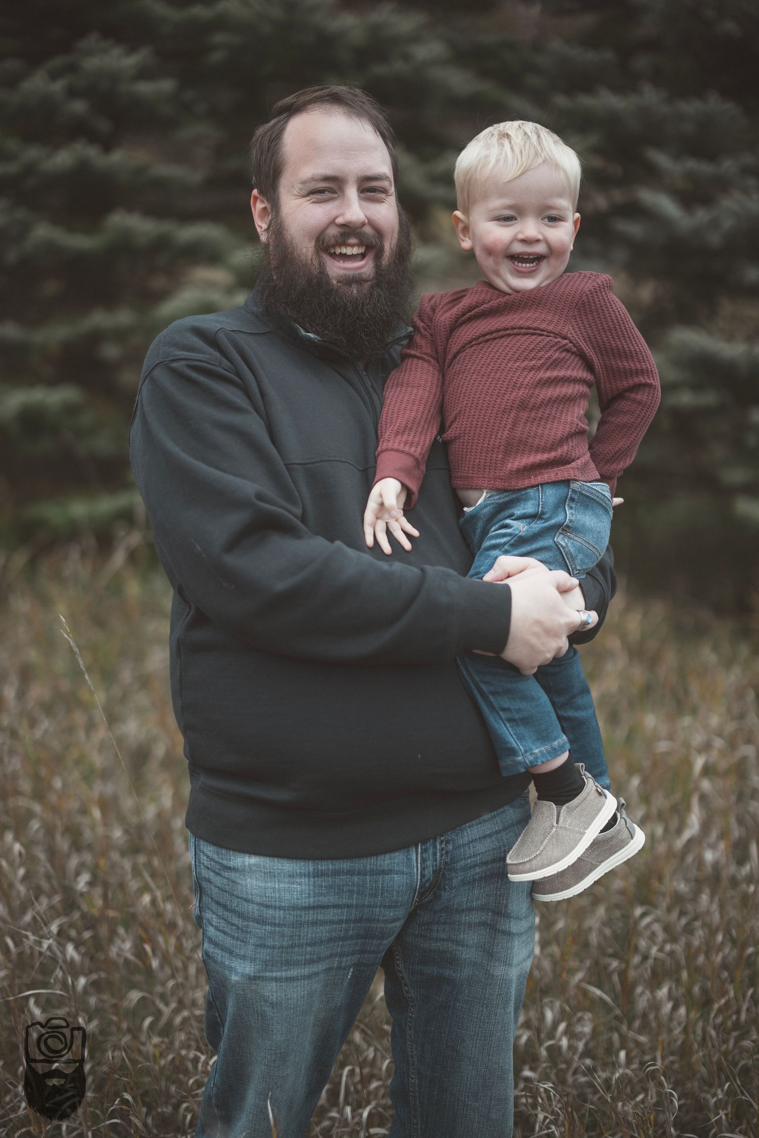 Playful family moment captured outdoors against evergreen trees.
