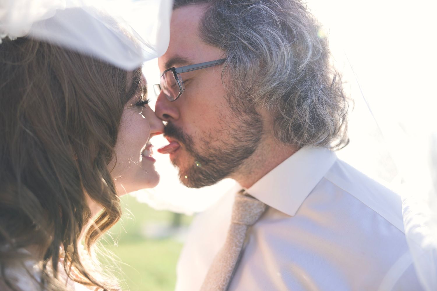 Intimate close-up of couple sharing tender moment in sunlit setting.