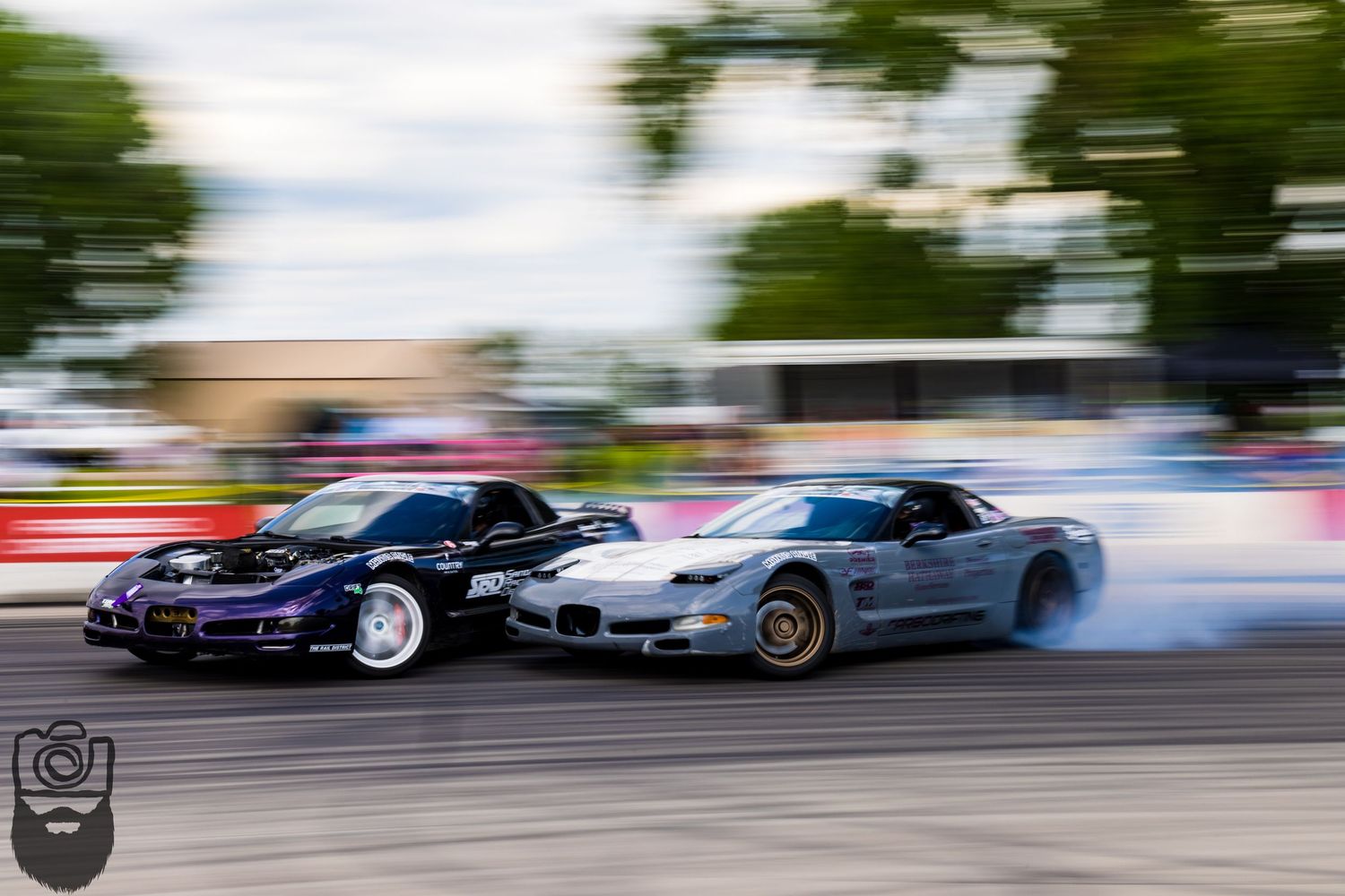 Racing cars sliding sideways in a drift competition with dramatic motion blur.