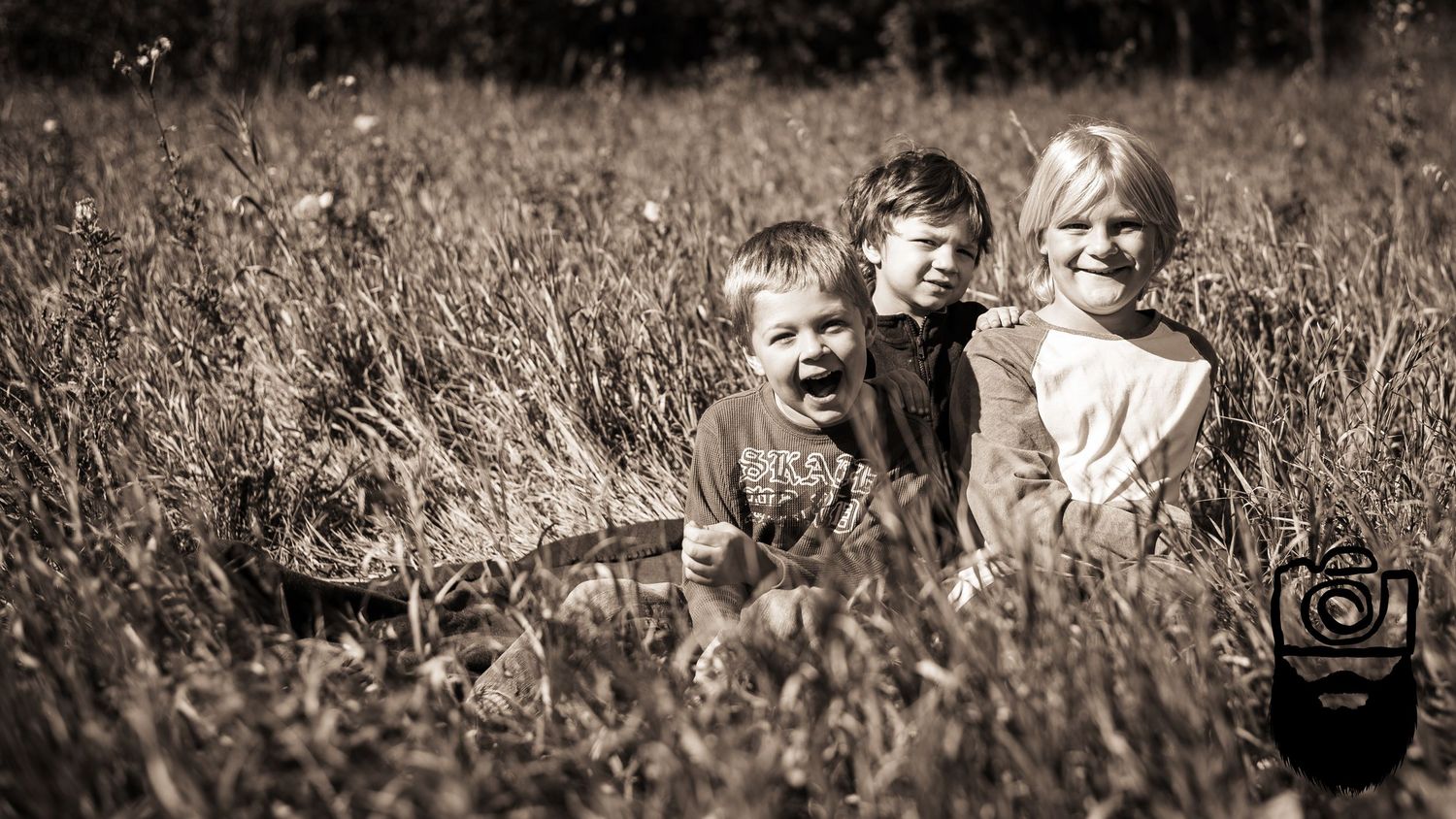 Panoramic sepia-toned family portrait in natural outdoor setting.