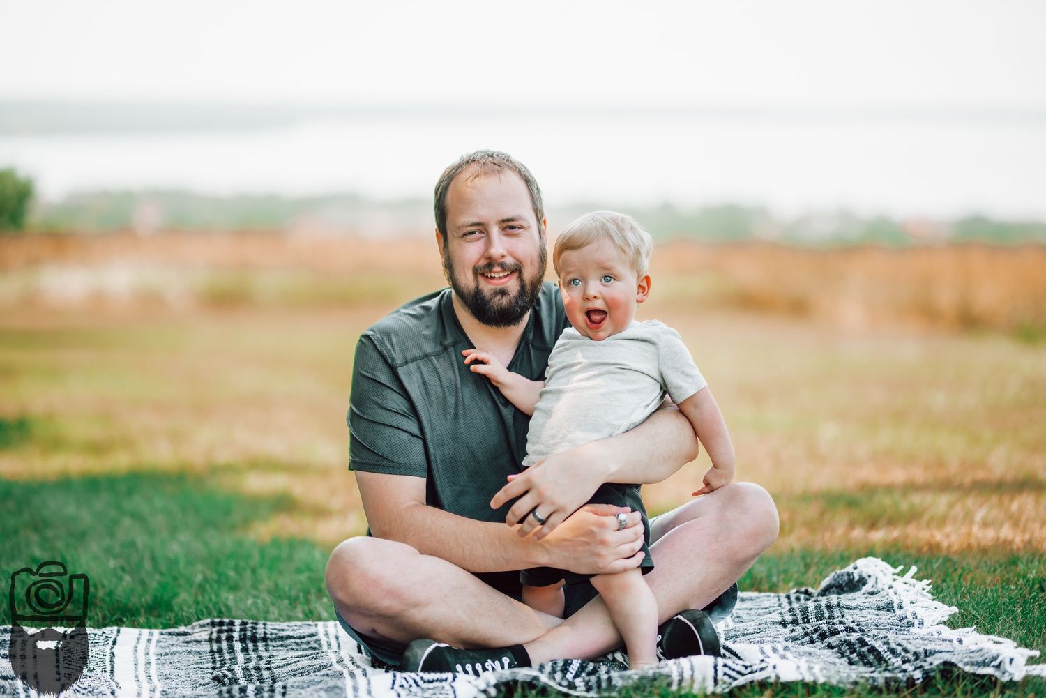 Family enjoying a tender moment together on a picnic blanket in a sunny outdoor field.