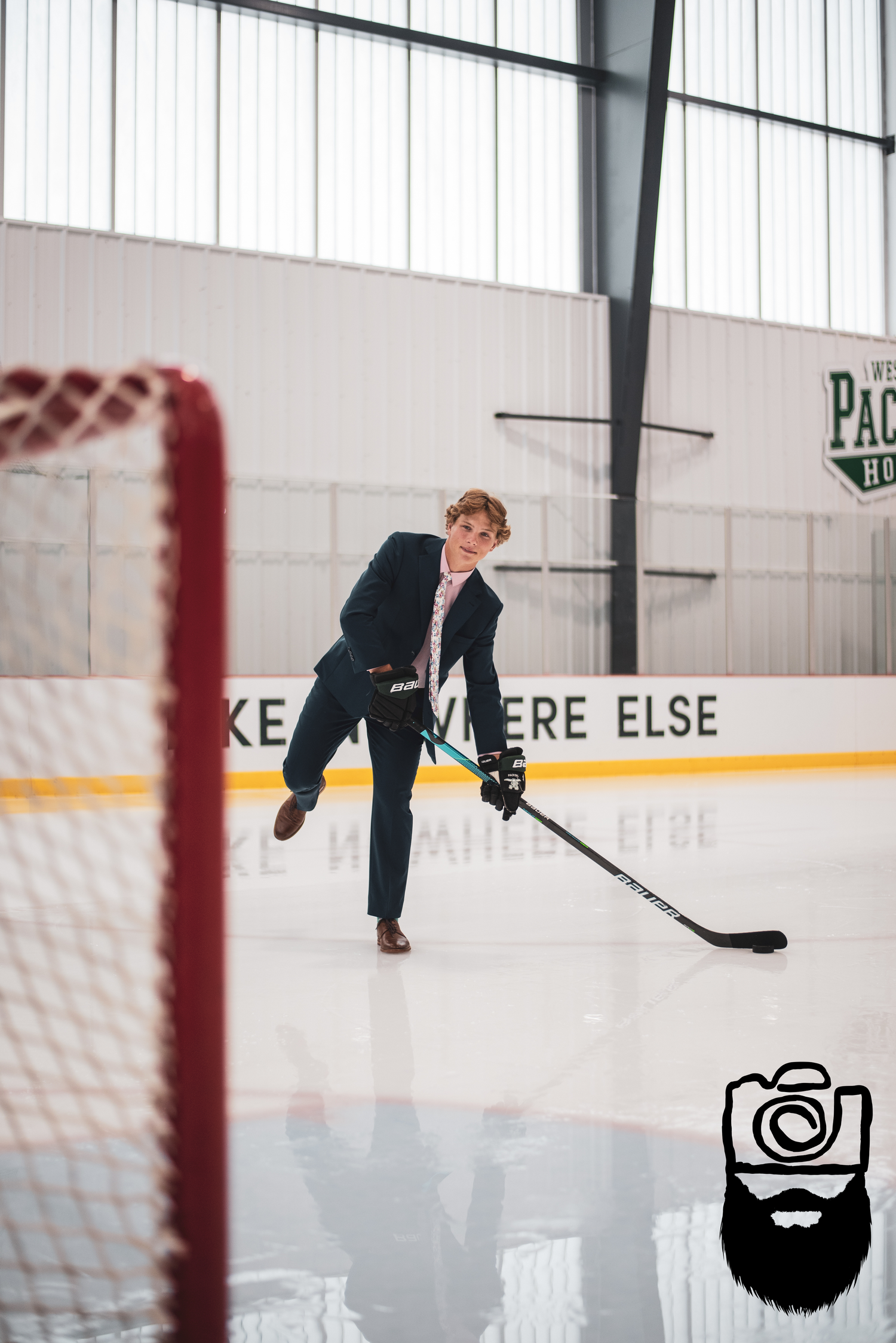Hockey player in formal attire practicing shots on indoor ice rink.